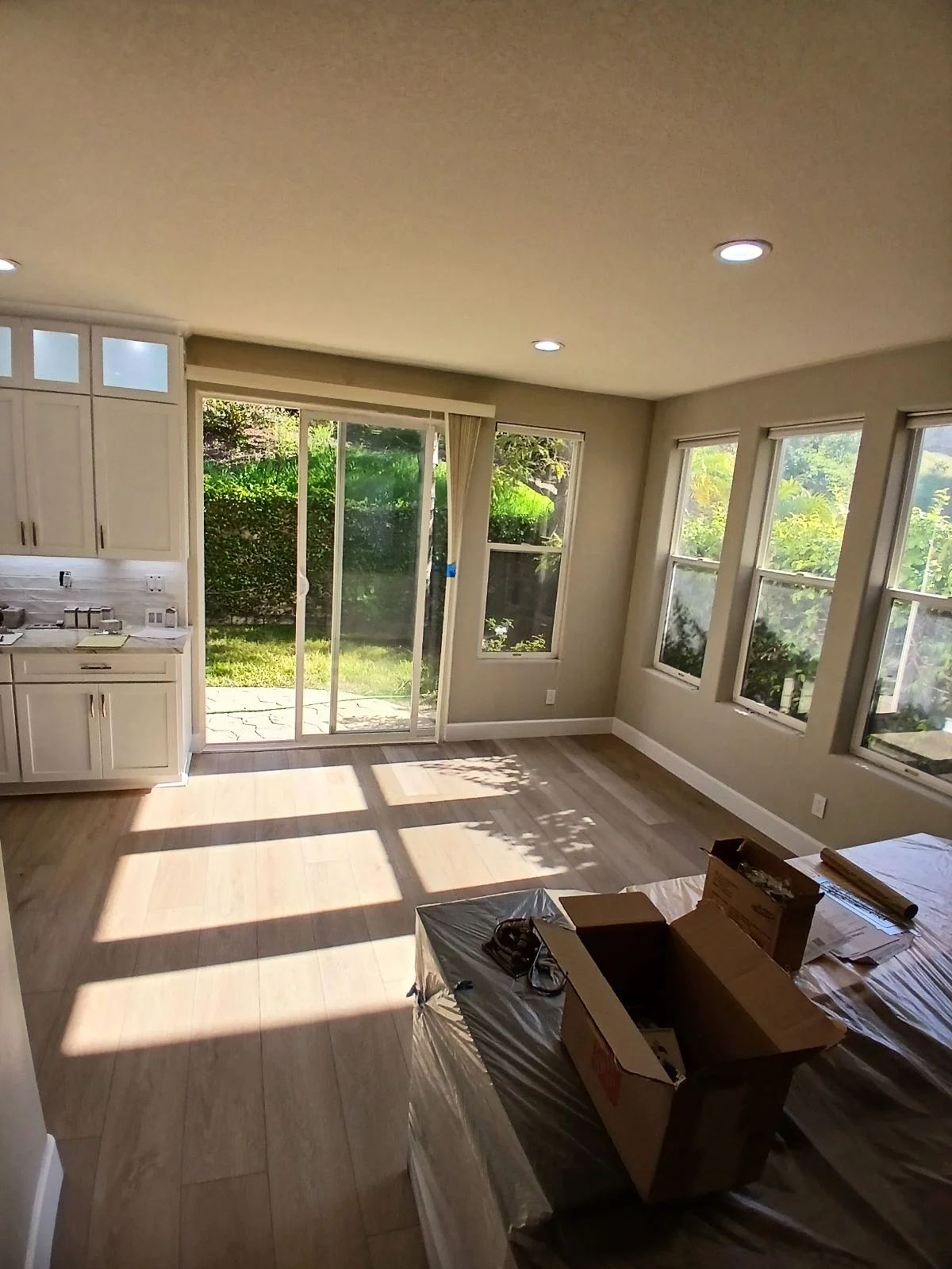 Kitchen with white cabinets, wood flooring, recessed lights, and sliding glass doors opening to patio