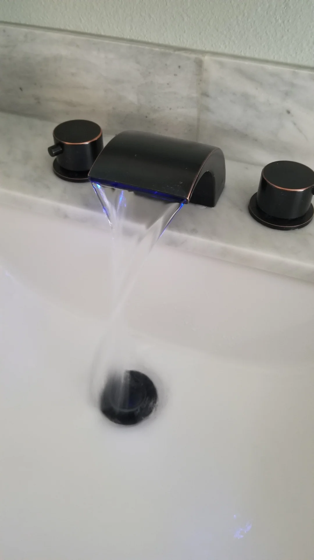 Matte black bathroom faucet with LED lighting on white marble vanity