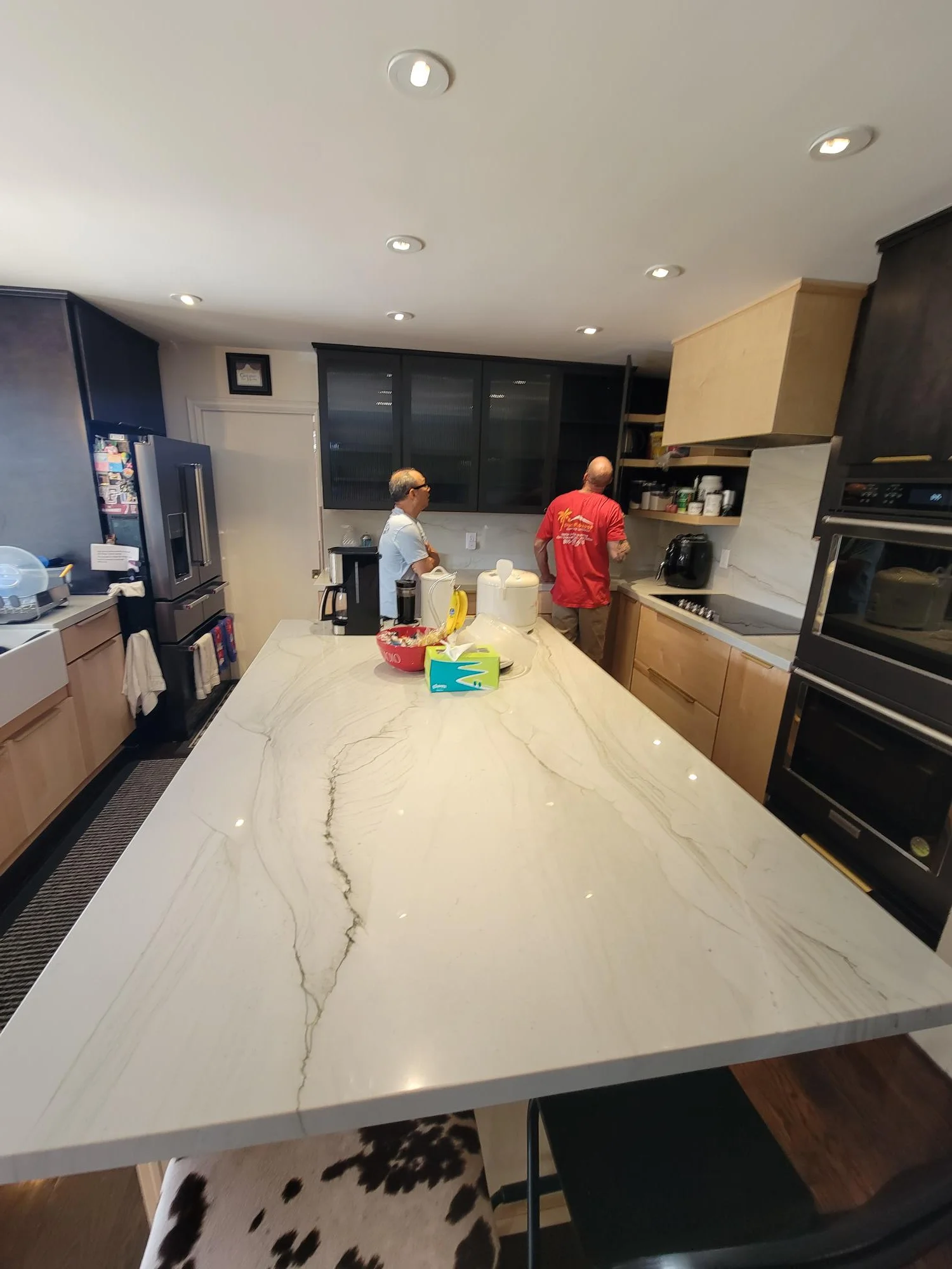 Kitchen with white quartz island countertop, wood and white cabinetry, stainless steel appliances, and recessed lighting