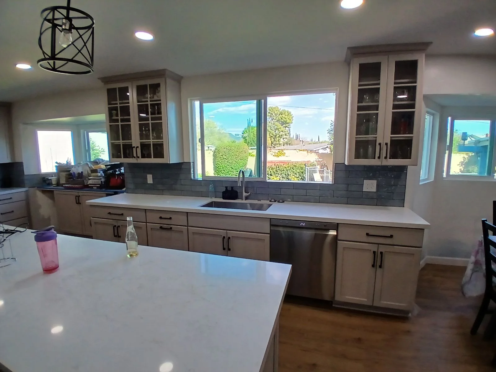 Kitchen with taupe cabinets, white quartz counters, gray subway tile backsplash, and large windows