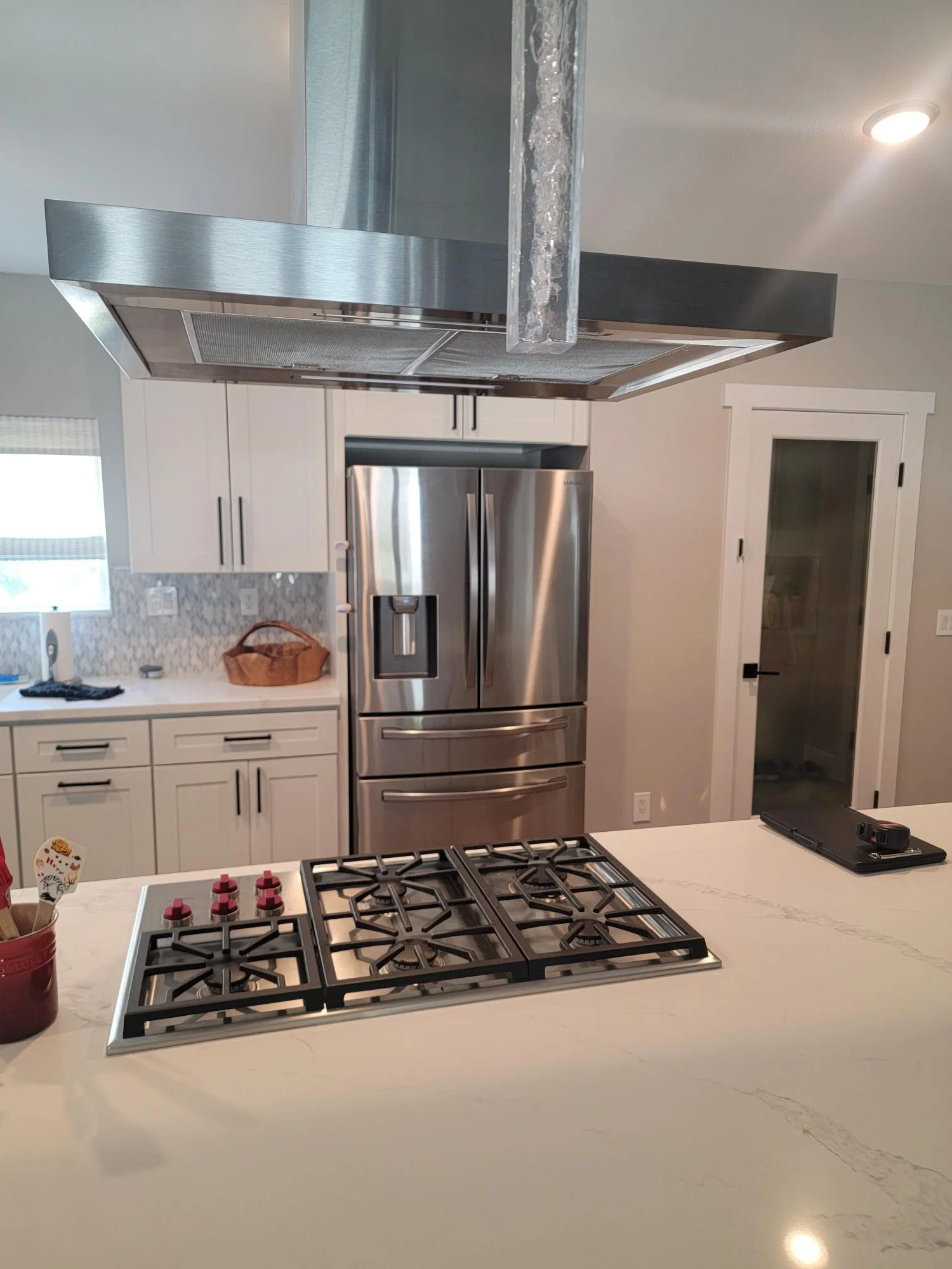 Modern kitchen with white cabinets, stainless steel appliances, quartz island countertop, and six-burner gas cooktop