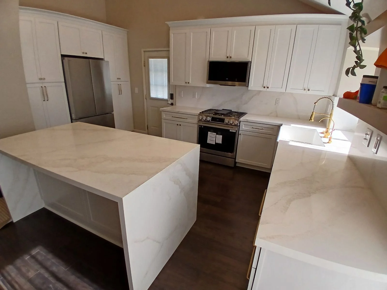 White kitchen cabinetry, quartz countertops, stainless steel appliances, gas range, hardwood flooring