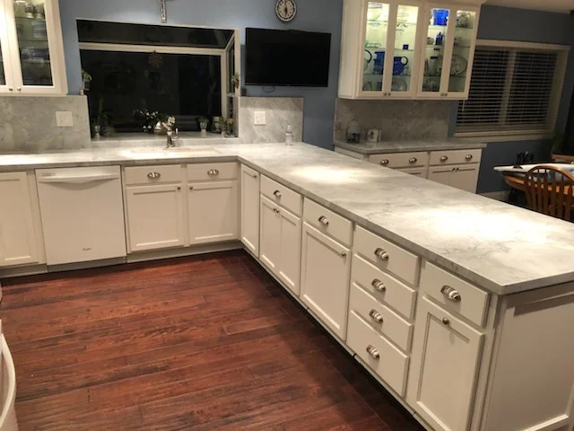 White kitchen cabinets with quartz countertops, hardwood flooring, and large island