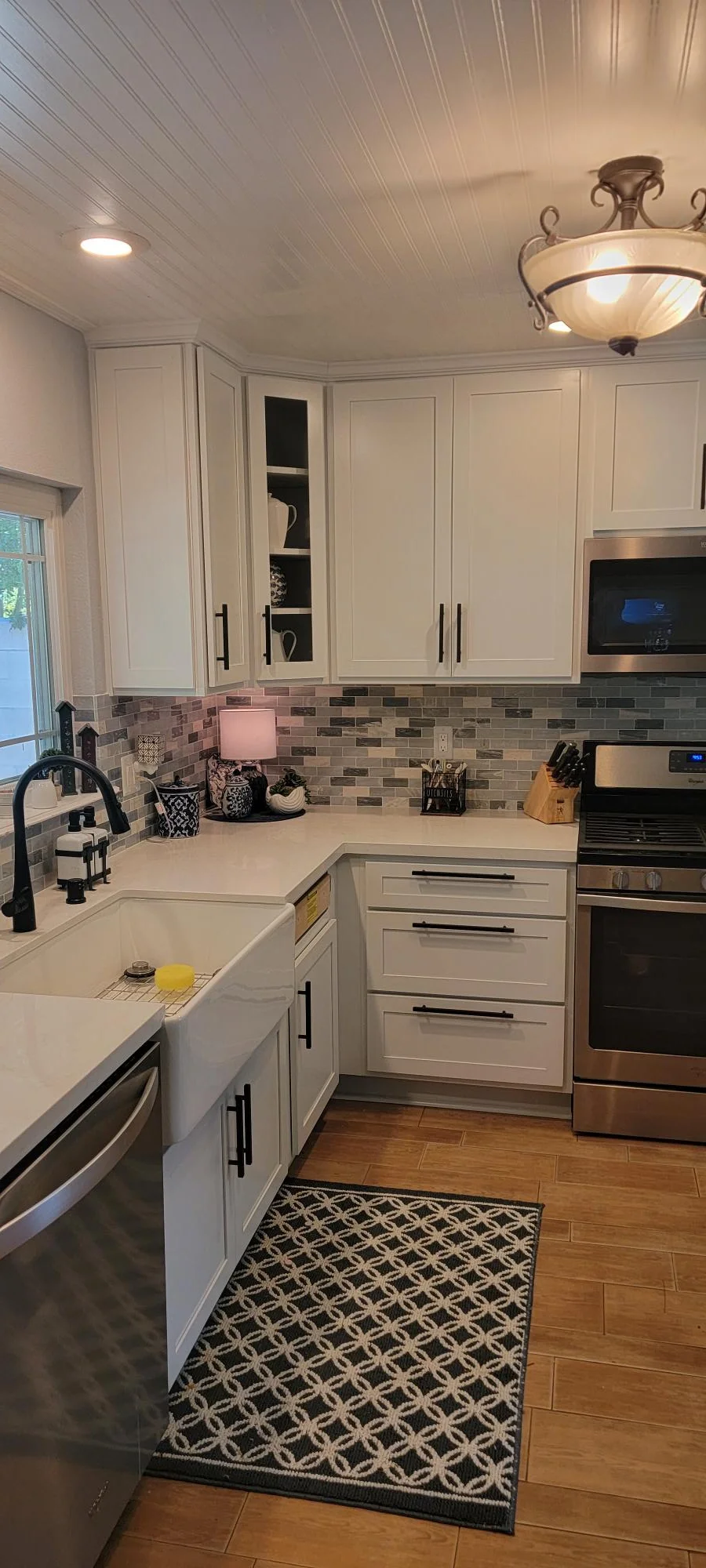 White kitchen with quartz counters, subway tile backsplash, stainless steel appliances, and beadboard ceiling
