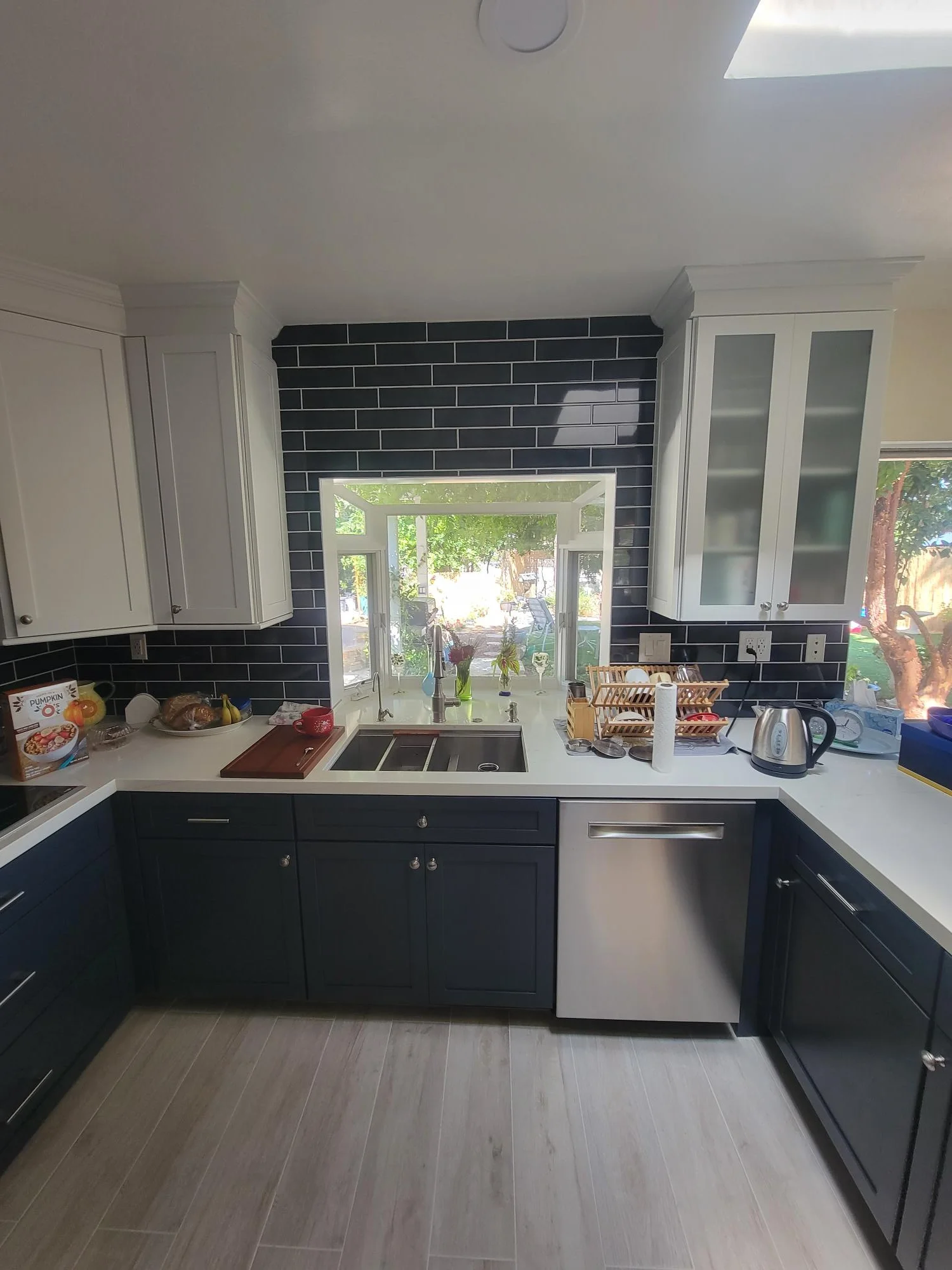 Kitchen with navy and white cabinets, black subway tile backsplash, white counters, stainless steel appliances