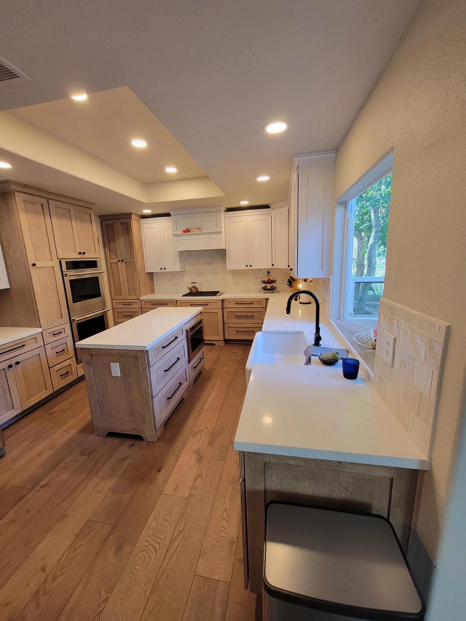 Modern kitchen with light wood cabinets, white quartz counters, island, and recessed lighting