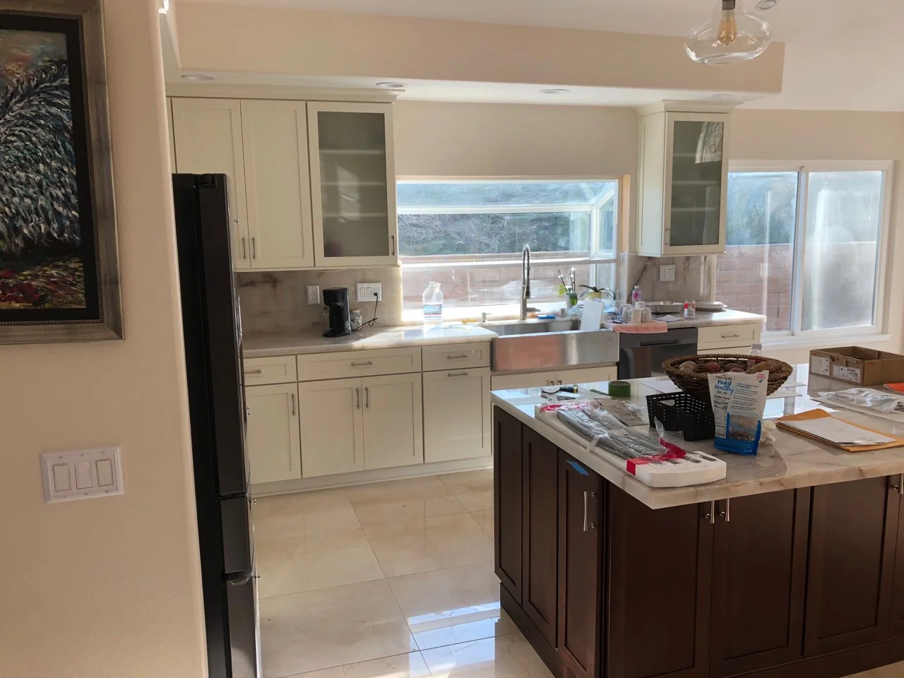 Kitchen with cream and dark wood cabinetry, stainless steel sink, tile flooring, and island