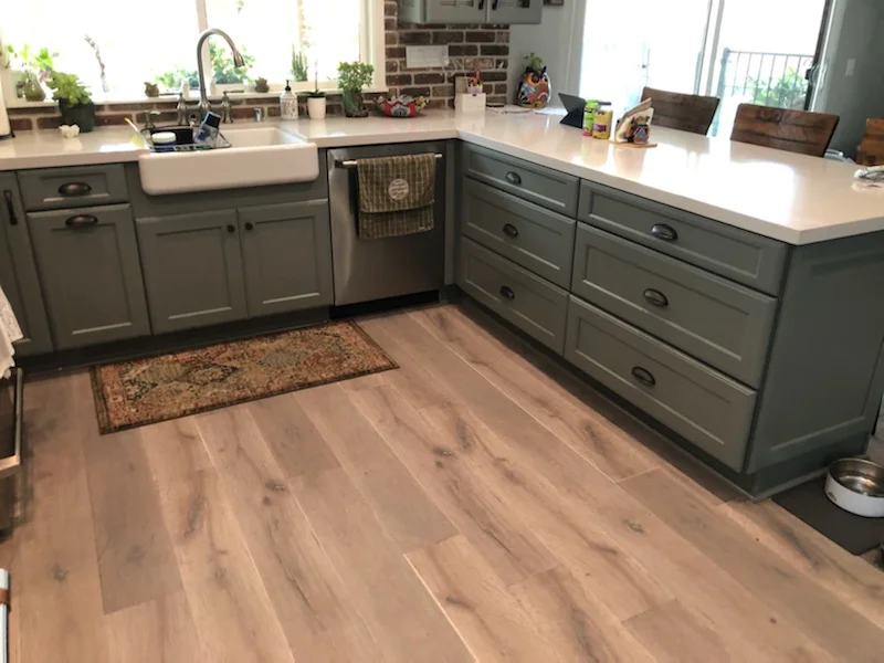Kitchen with sage green cabinets, white quartz counters, and wide-plank hardwood flooring