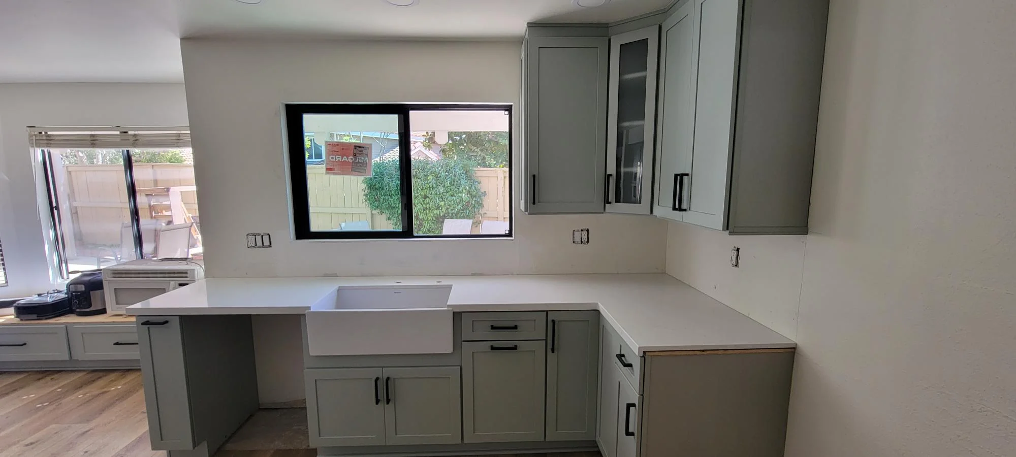Kitchen with sage green cabinets, white quartz counters, farmhouse sink, and black-framed windows