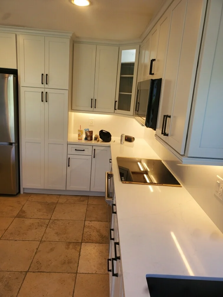 White kitchen cabinetry with quartz countertops, stainless steel appliances, and under-cabinet lighting