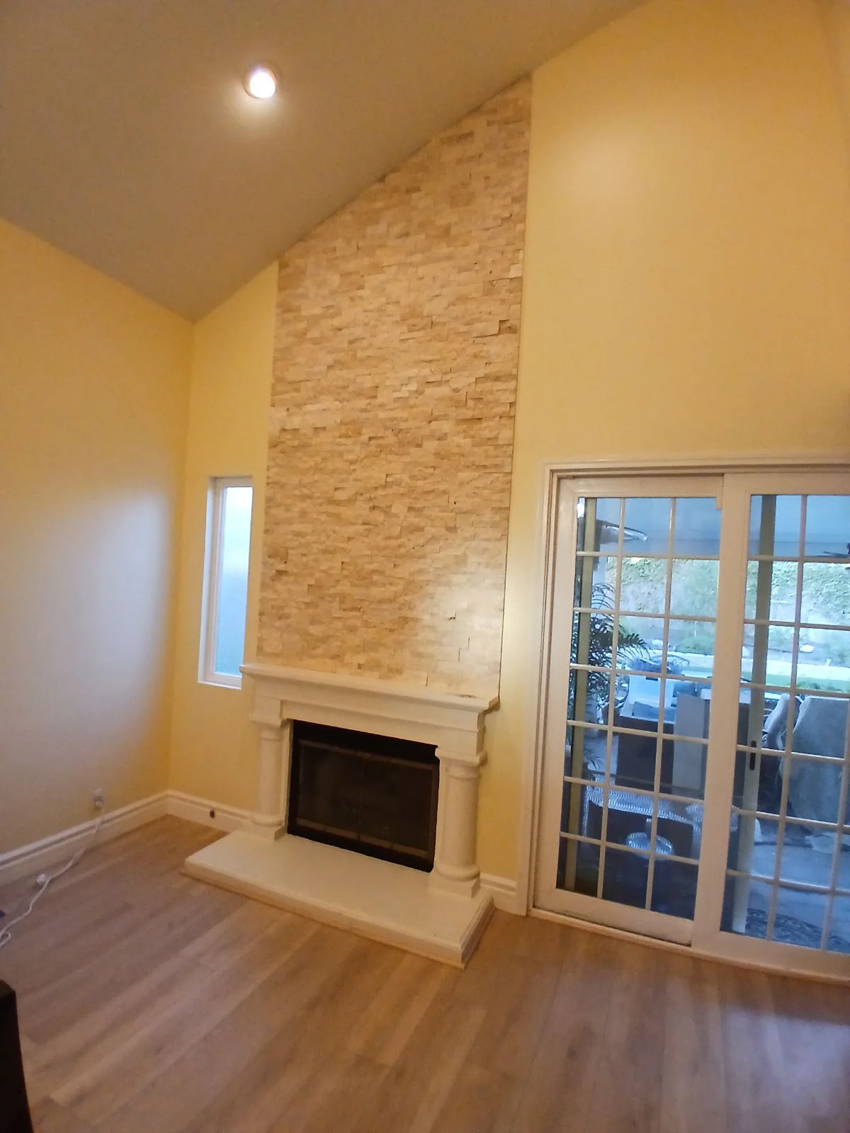 Stacked stone fireplace wall with white mantel, yellow painted drywall, hardwood floors, and French doors