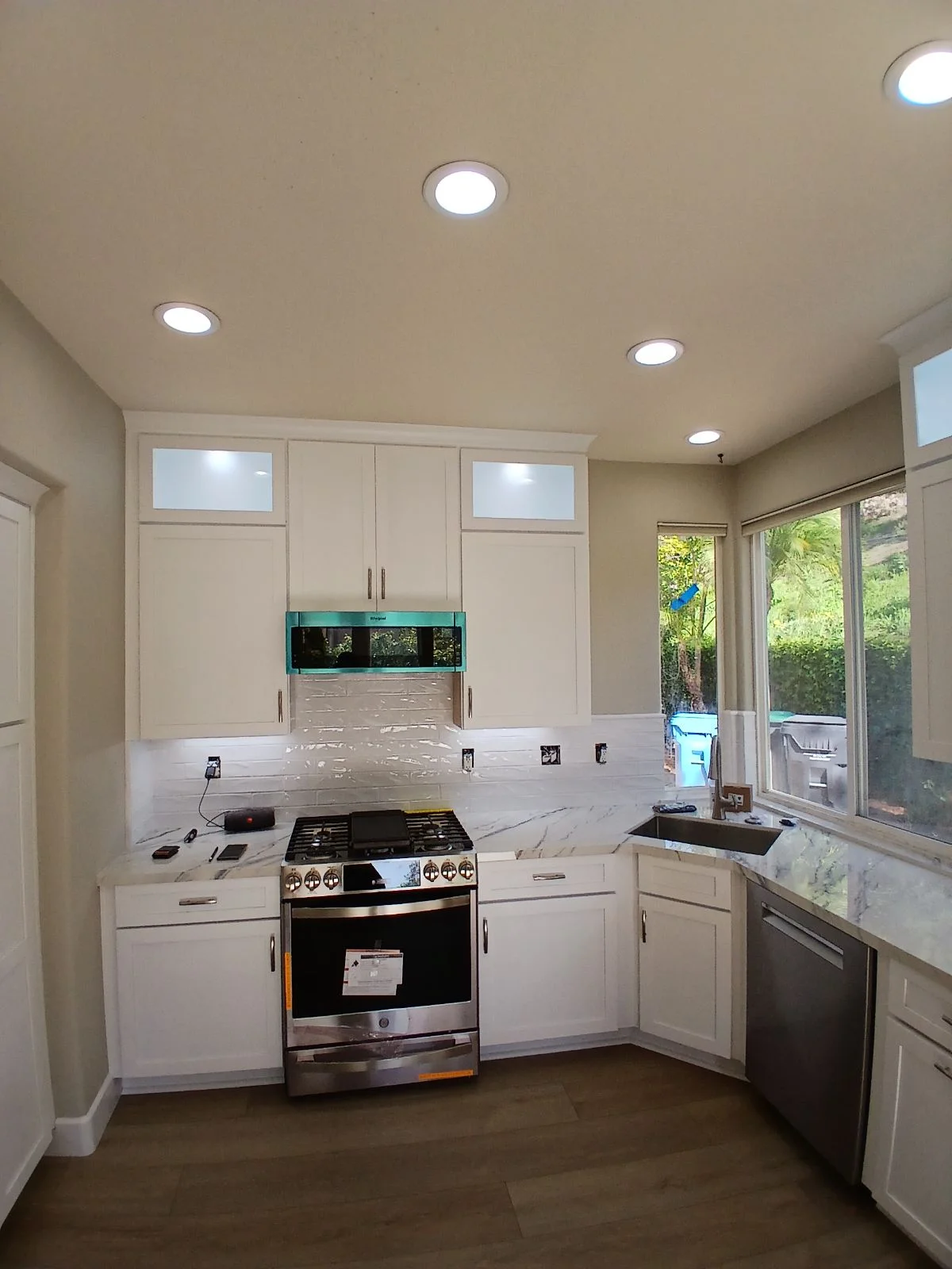 White kitchen with marble counters, gas range, custom cabinetry, and turquoise backsplash tile