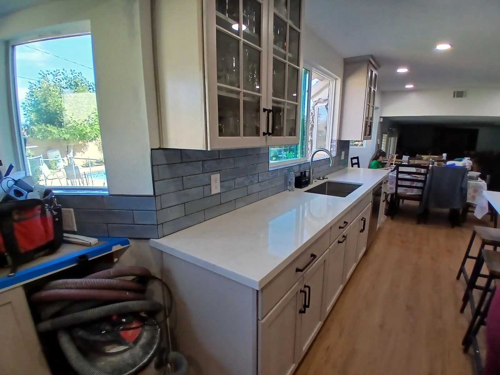 Kitchen with white quartz island, dark subway tile backsplash, and custom cabinetry