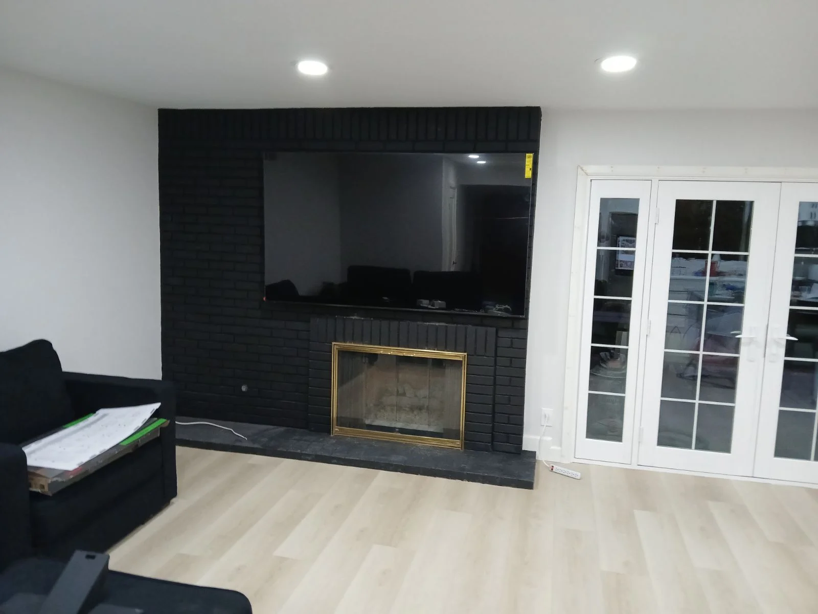 Black brick fireplace surround with gold-trimmed fireplace insert, mounted TV, and slate hearth