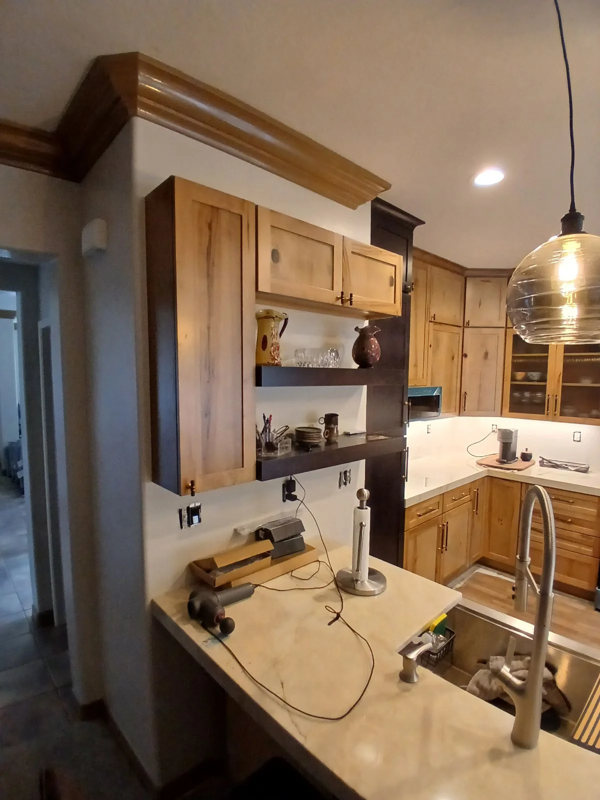 Kitchen with wood cabinetry, white quartz counters, island sink, and pendant lighting
