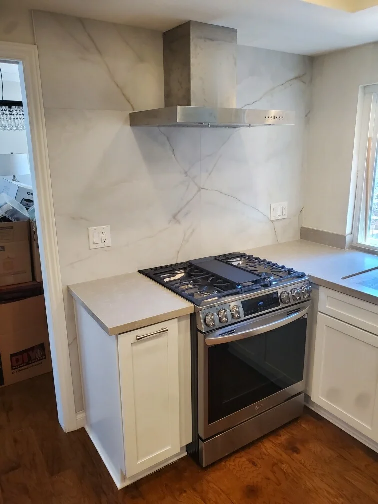 Kitchen with marble backsplash, white cabinetry, stainless steel range, and quartz countertops