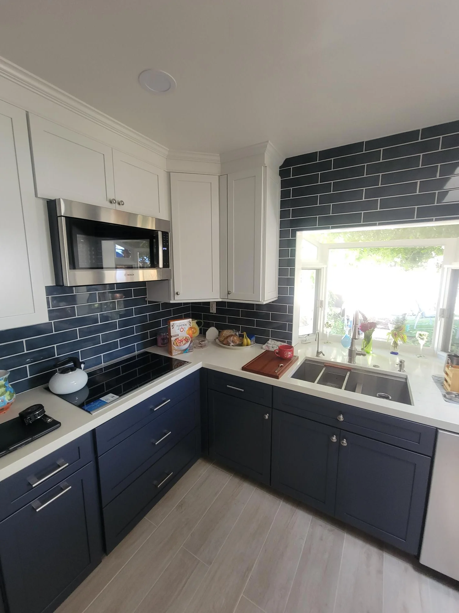 Kitchen with white and navy cabinetry, dark subway tile backsplash, quartz counters, stainless appliances
