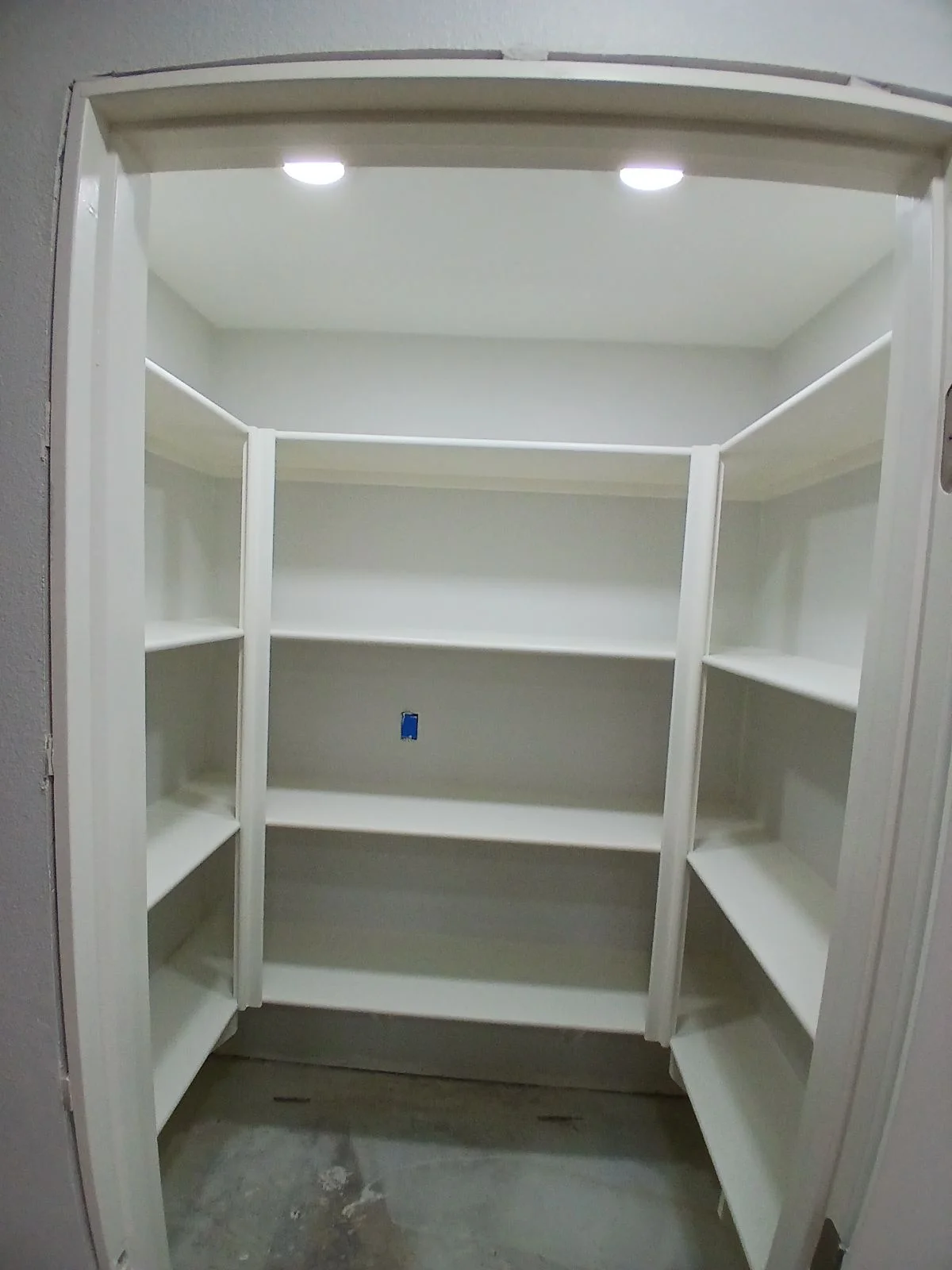 White built-in shelving with recessed LED lighting and multiple compartments in closet