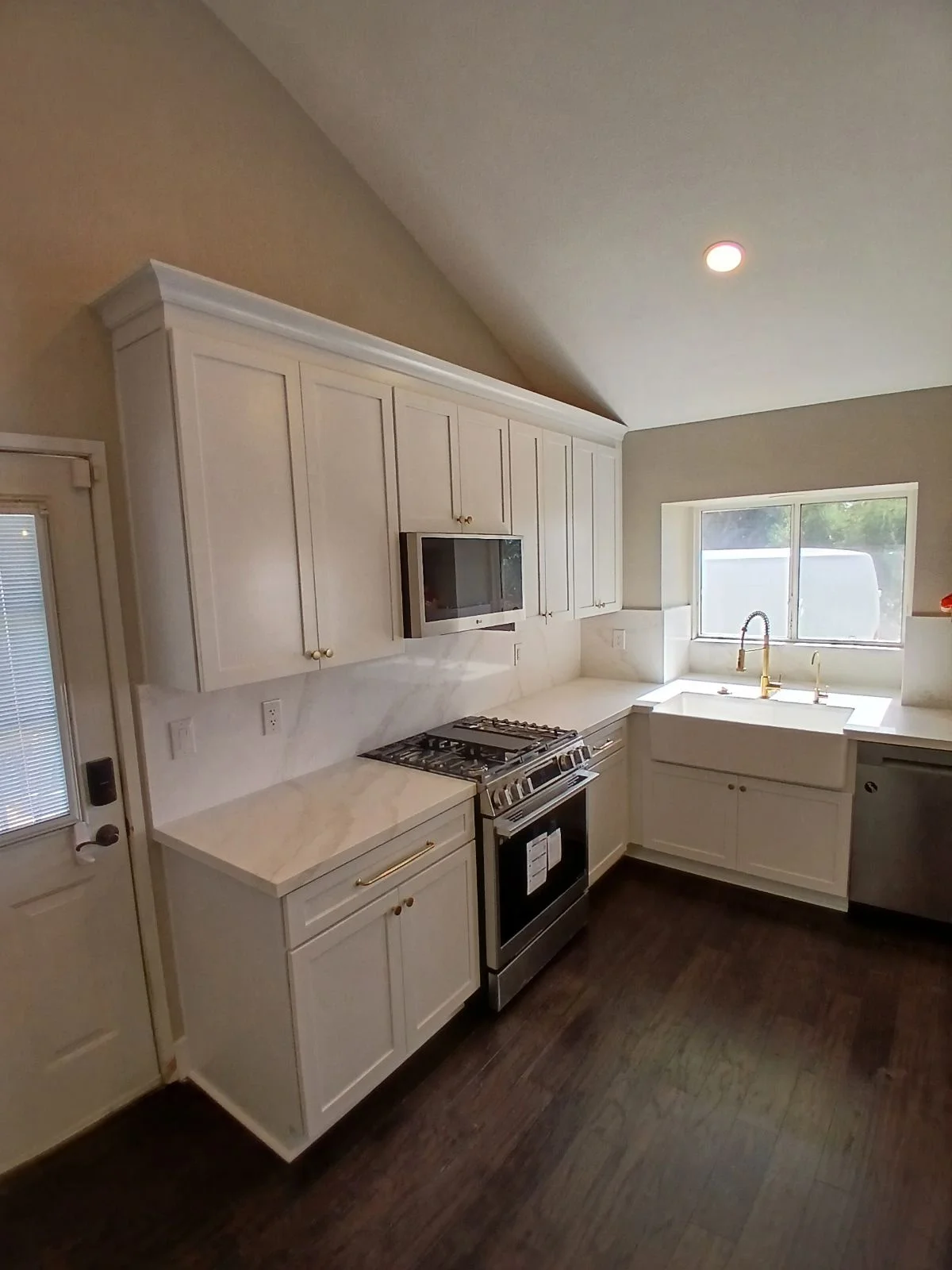 White kitchen cabinetry with quartz counters, stainless steel range, and recessed lighting in vaulted ceiling