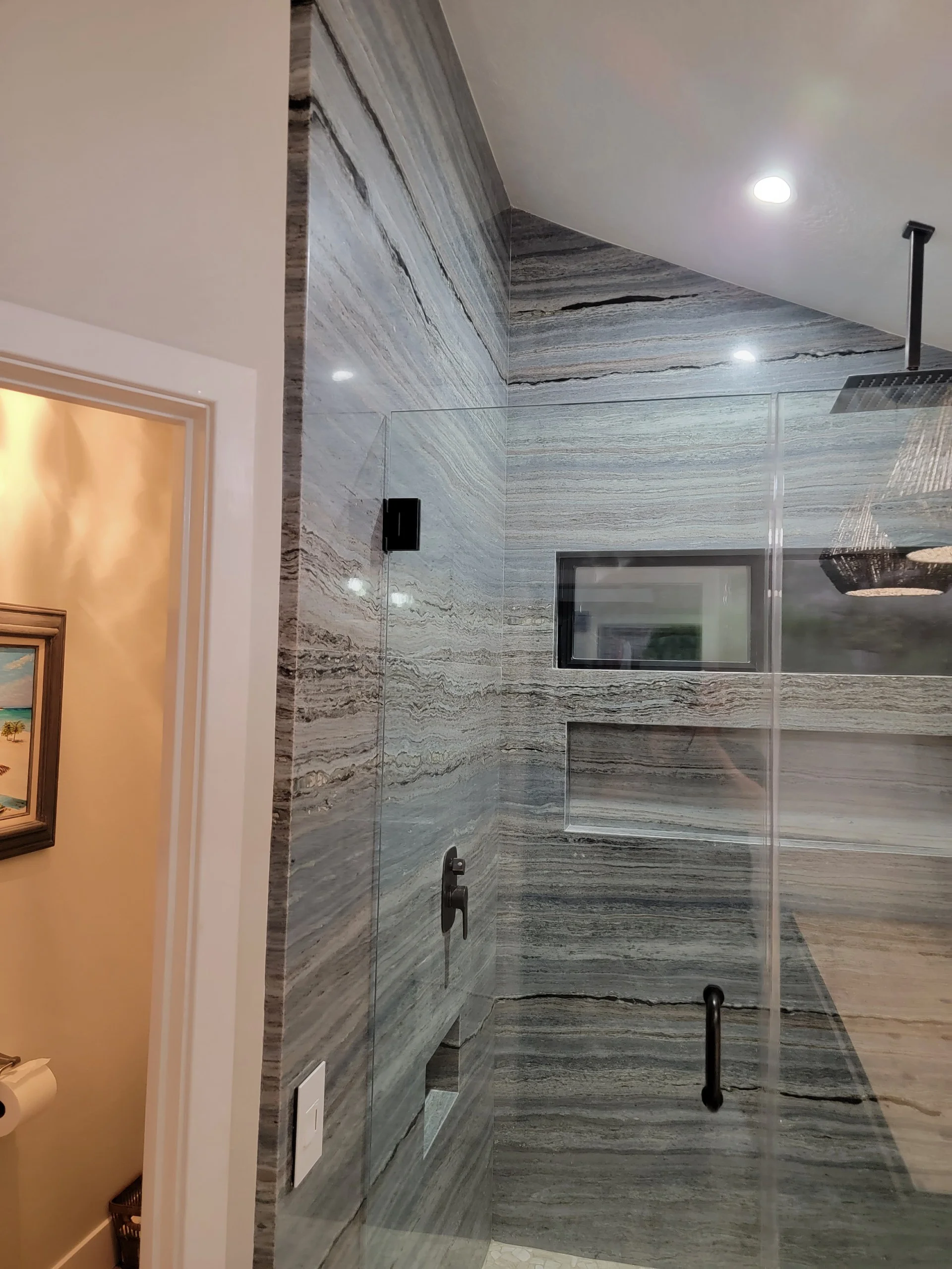 Gray marble tile bathroom with frameless glass shower enclosure and recessed lighting