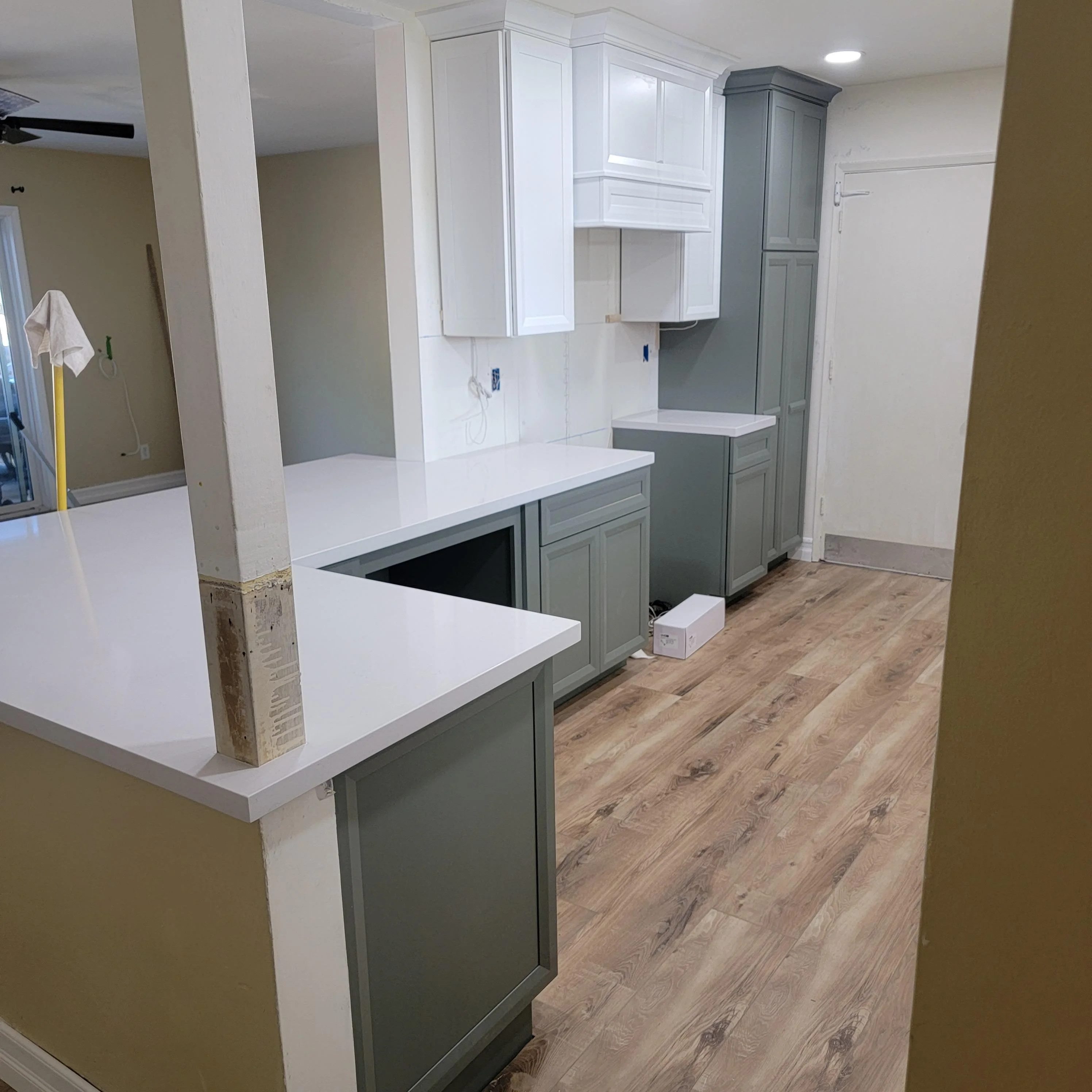Kitchen with gray and white cabinetry, white quartz counters, and wood-look vinyl plank flooring
