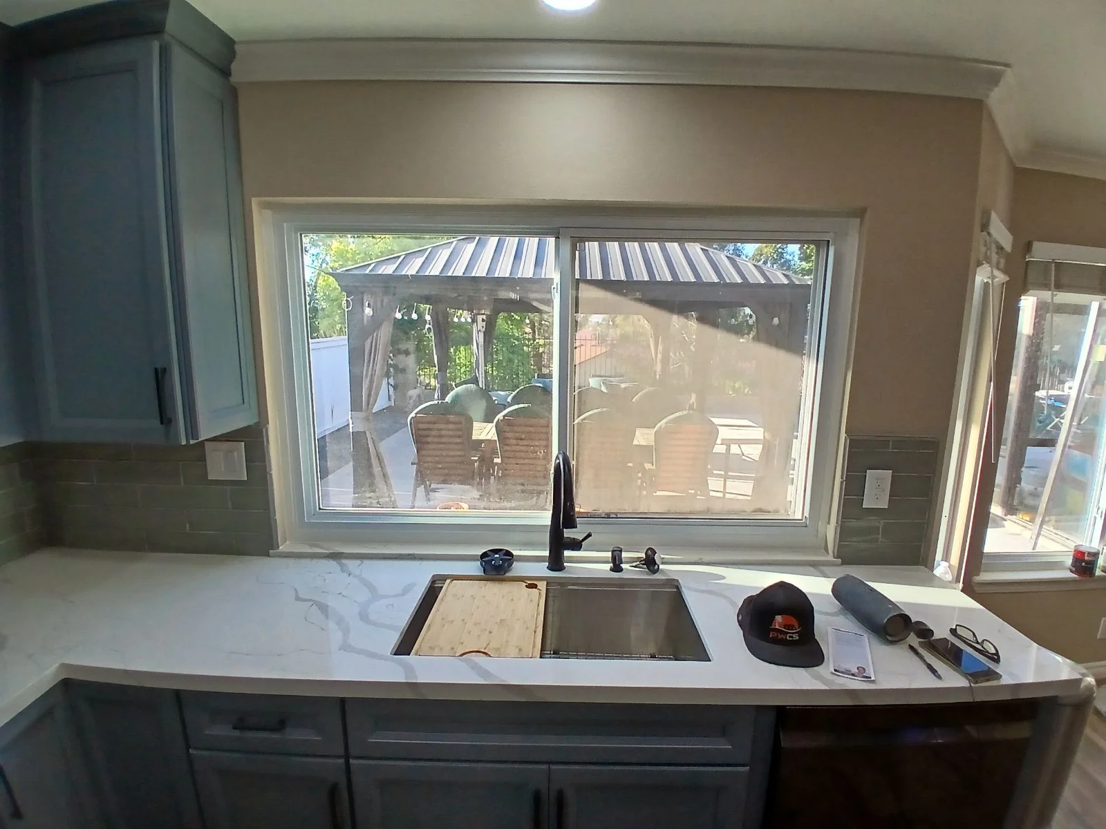Kitchen with dual-pane sliding windows, dark cabinetry, quartz counters, and stainless steel sink