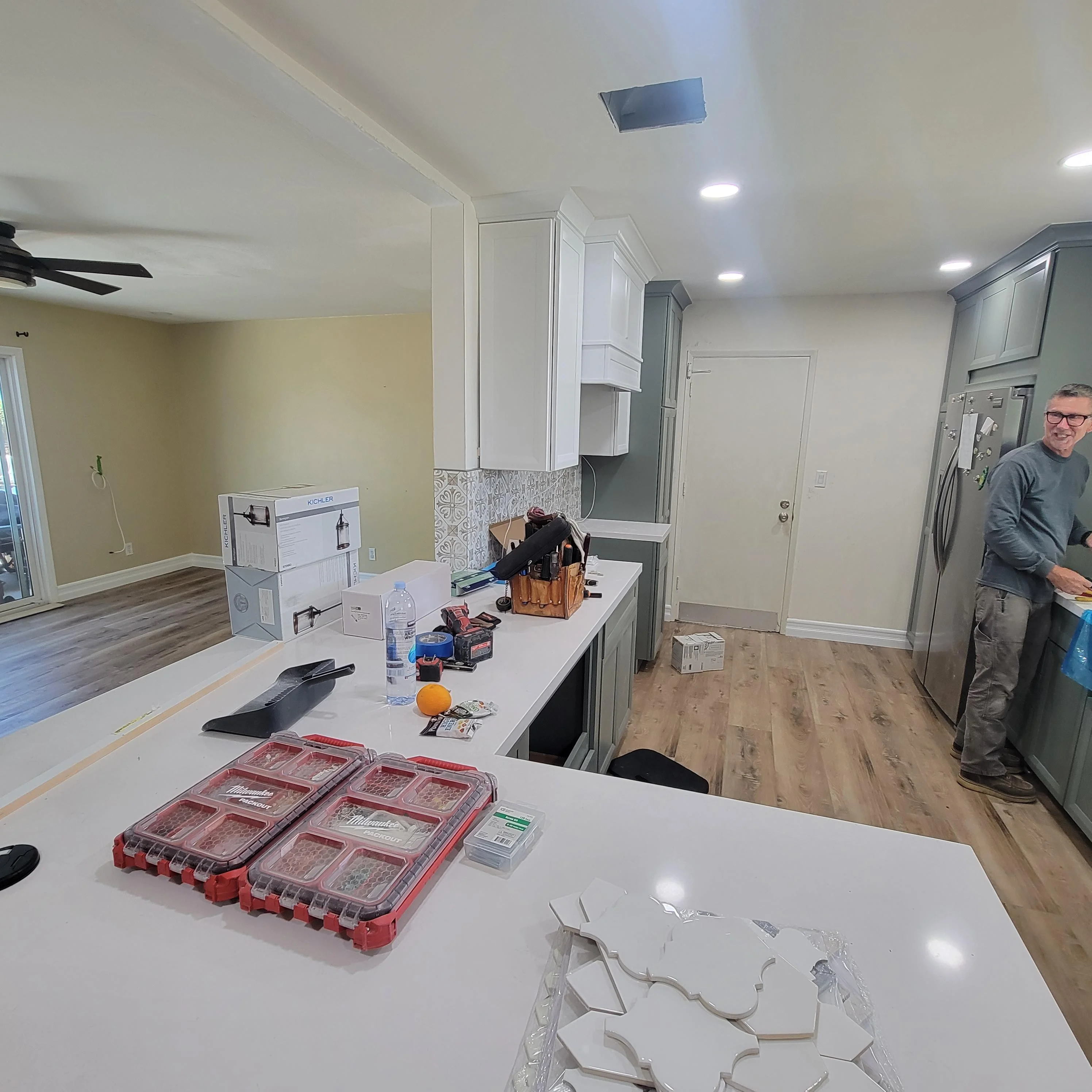 Kitchen renovation with white cabinetry, tile backsplash, stainless steel appliances, and hardwood flooring