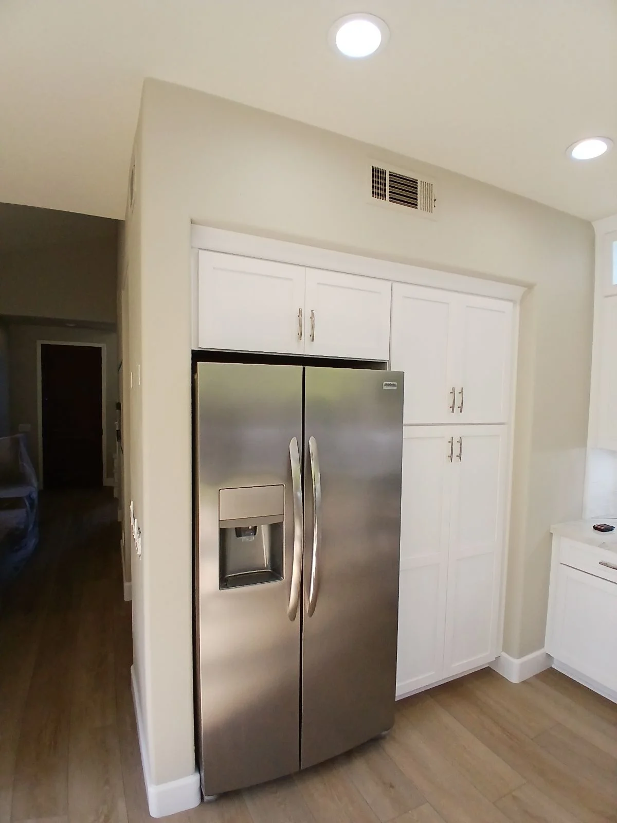 White kitchen cabinets with stainless steel refrigerator, recessed lighting, and HVAC vents