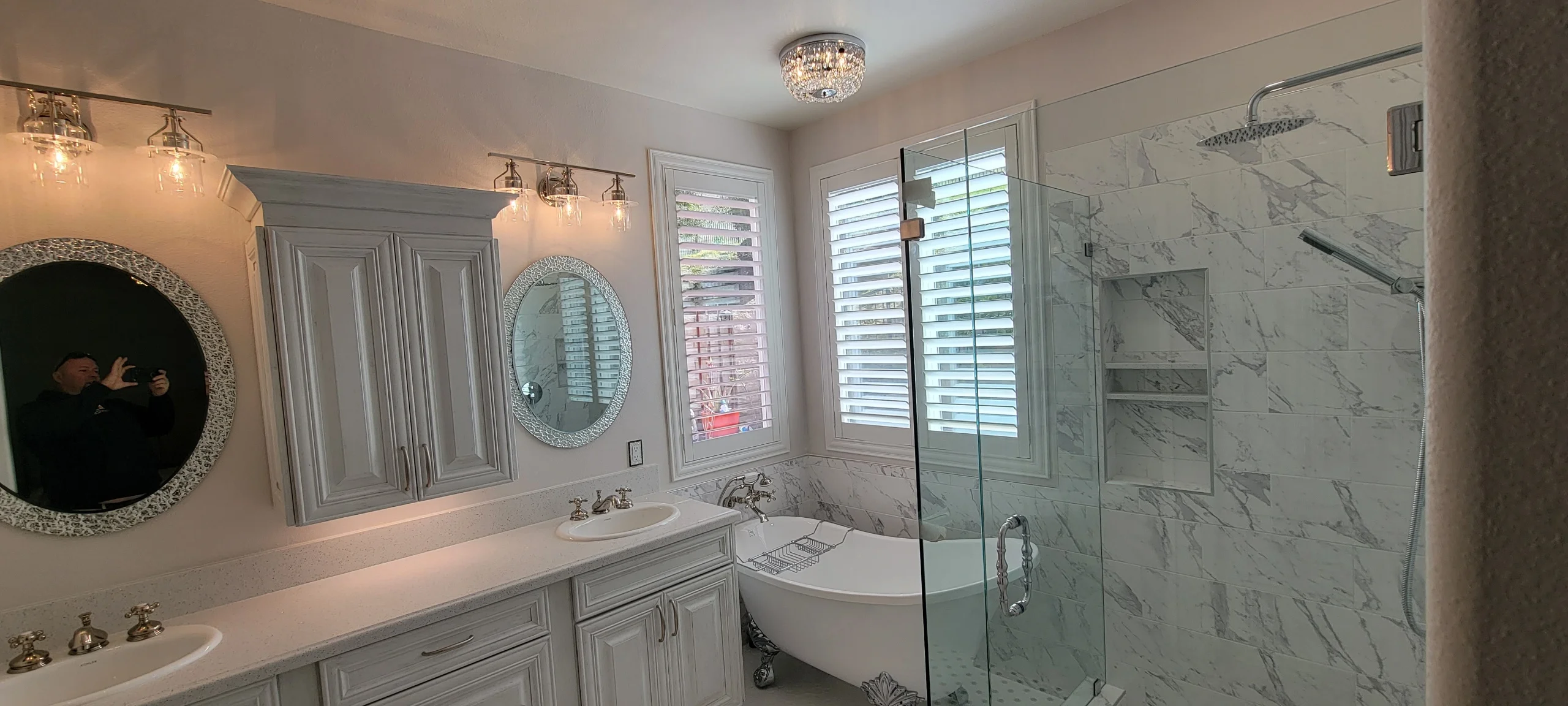 Master bathroom with marble tile shower, freestanding tub, dual vanity, and custom cabinetry