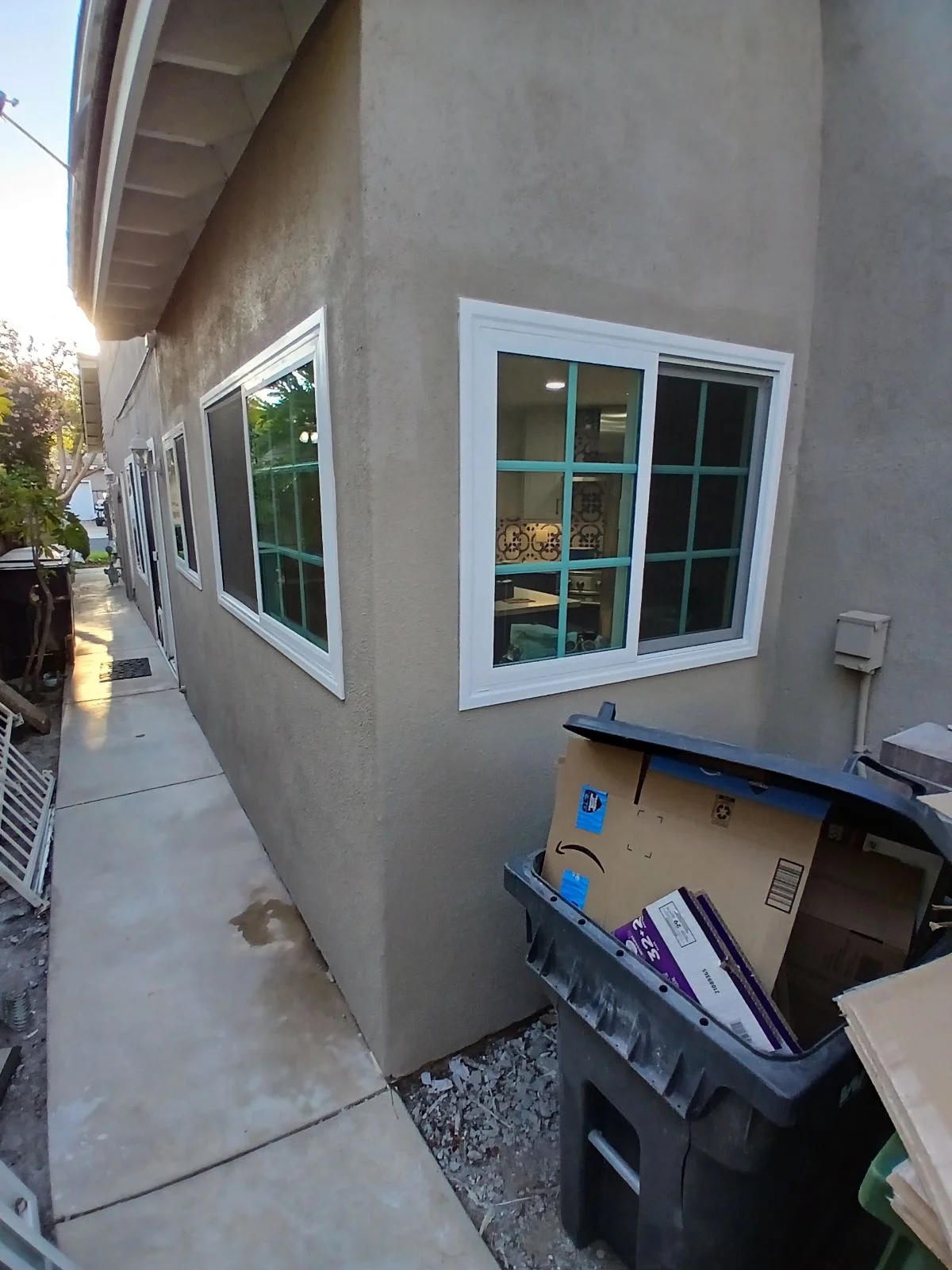 White-framed sliding glass doors and windows installed on stucco exterior wall with concrete patio