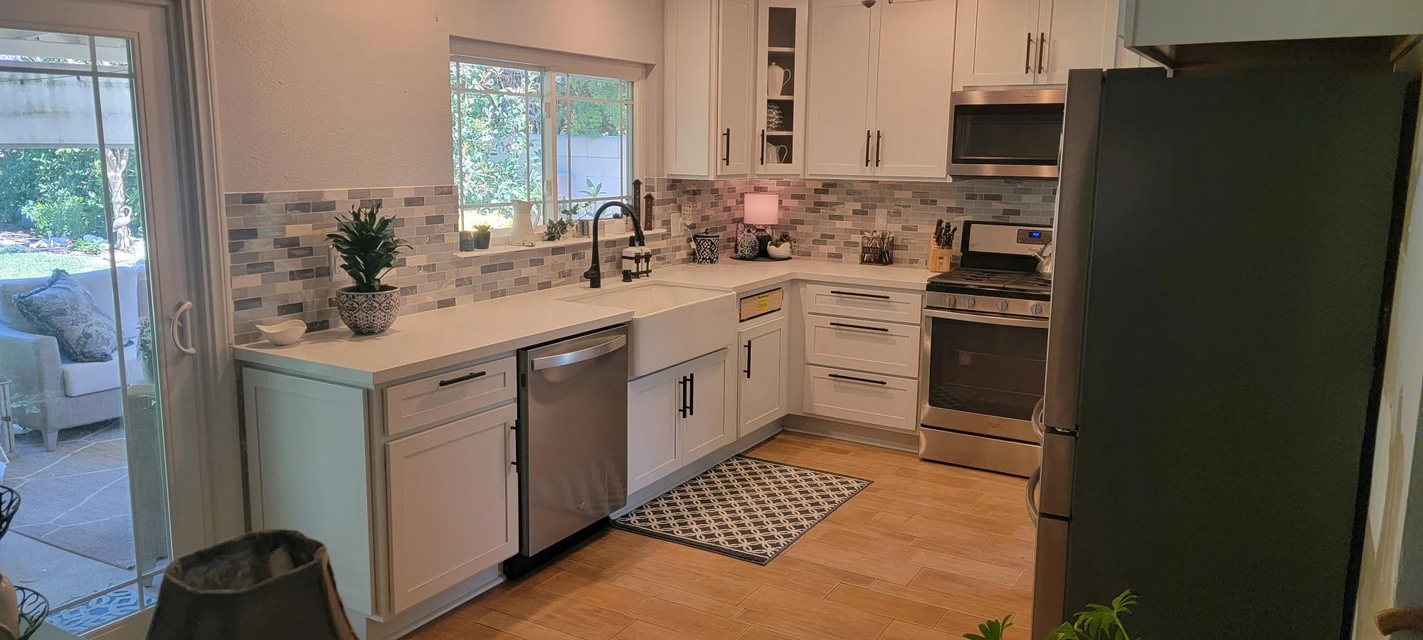 Kitchen with white cabinets, quartz counters, brick tile backsplash, stainless appliances, hardwood floors