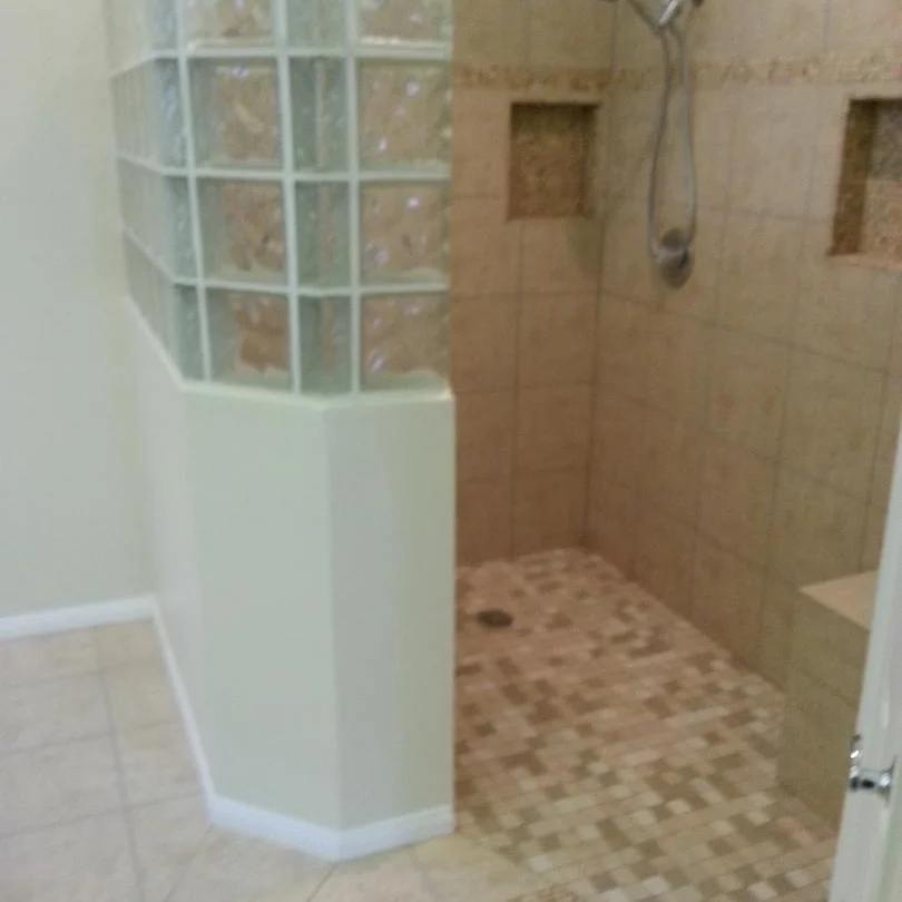 Curved glass block shower enclosure with tile flooring and updated bathroom finishes