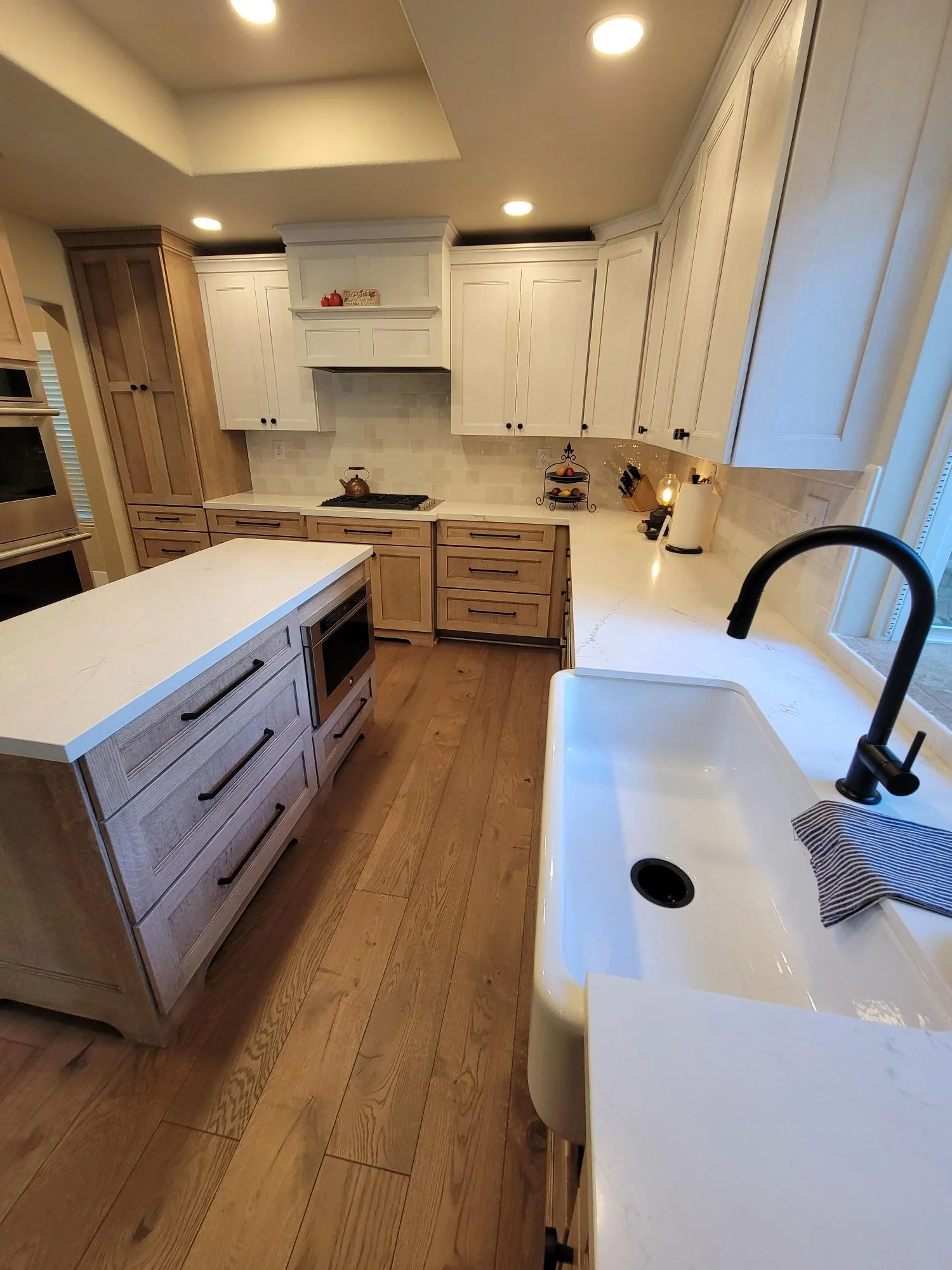 Kitchen with two-tone cabinetry, white quartz counters, island, hardwood floors, and recessed lighting