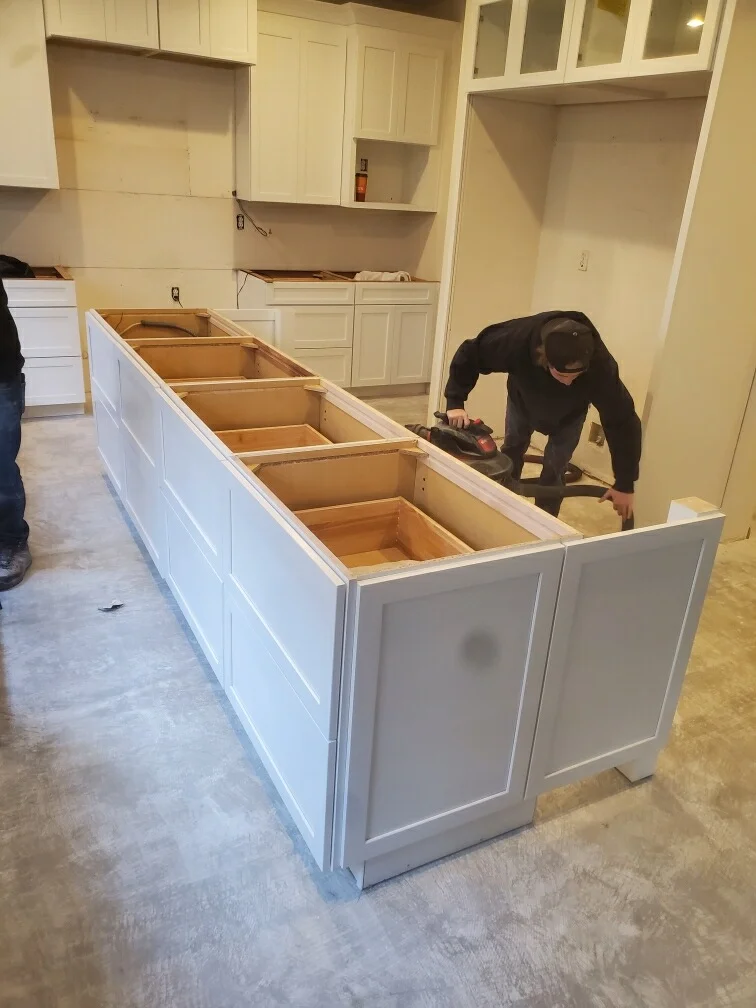 White painted kitchen island with open compartments during installation in residential kitchen