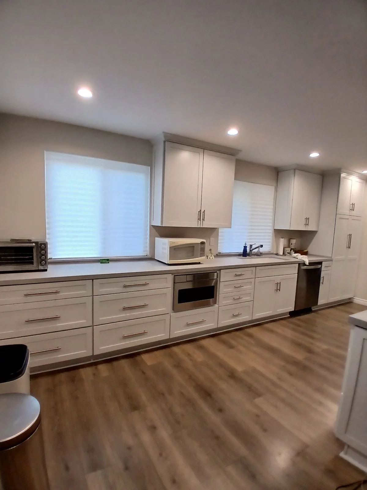 White kitchen cabinets, quartz counters, stainless steel appliances, recessed lighting, vinyl plank flooring