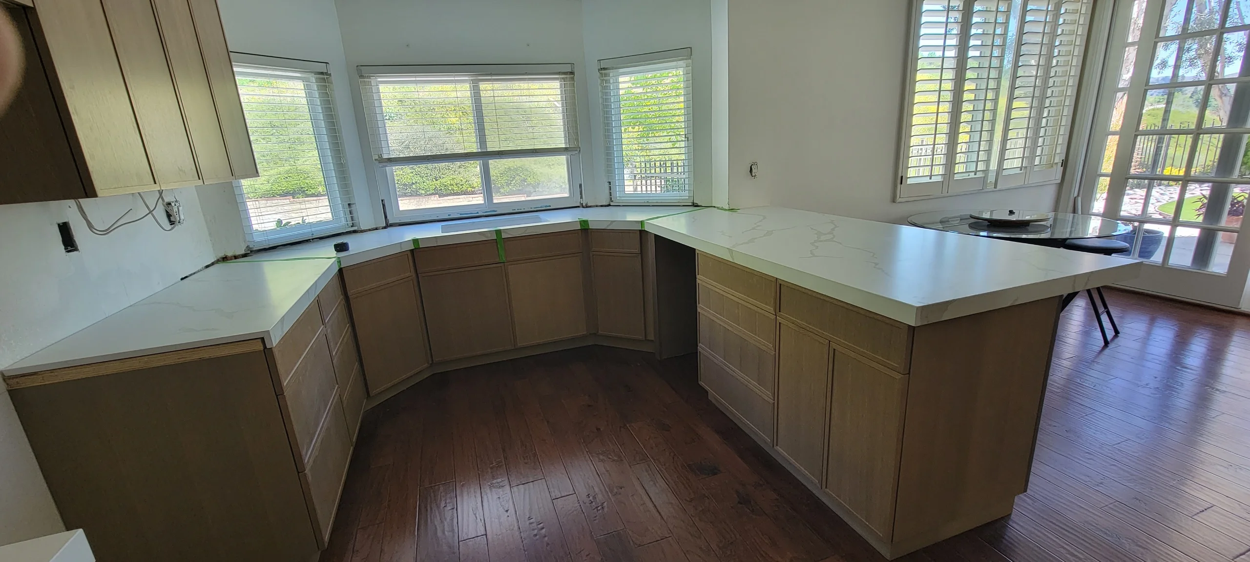 Kitchen with brown cabinetry, white quartz counters, dark hardwood floors, and curved island