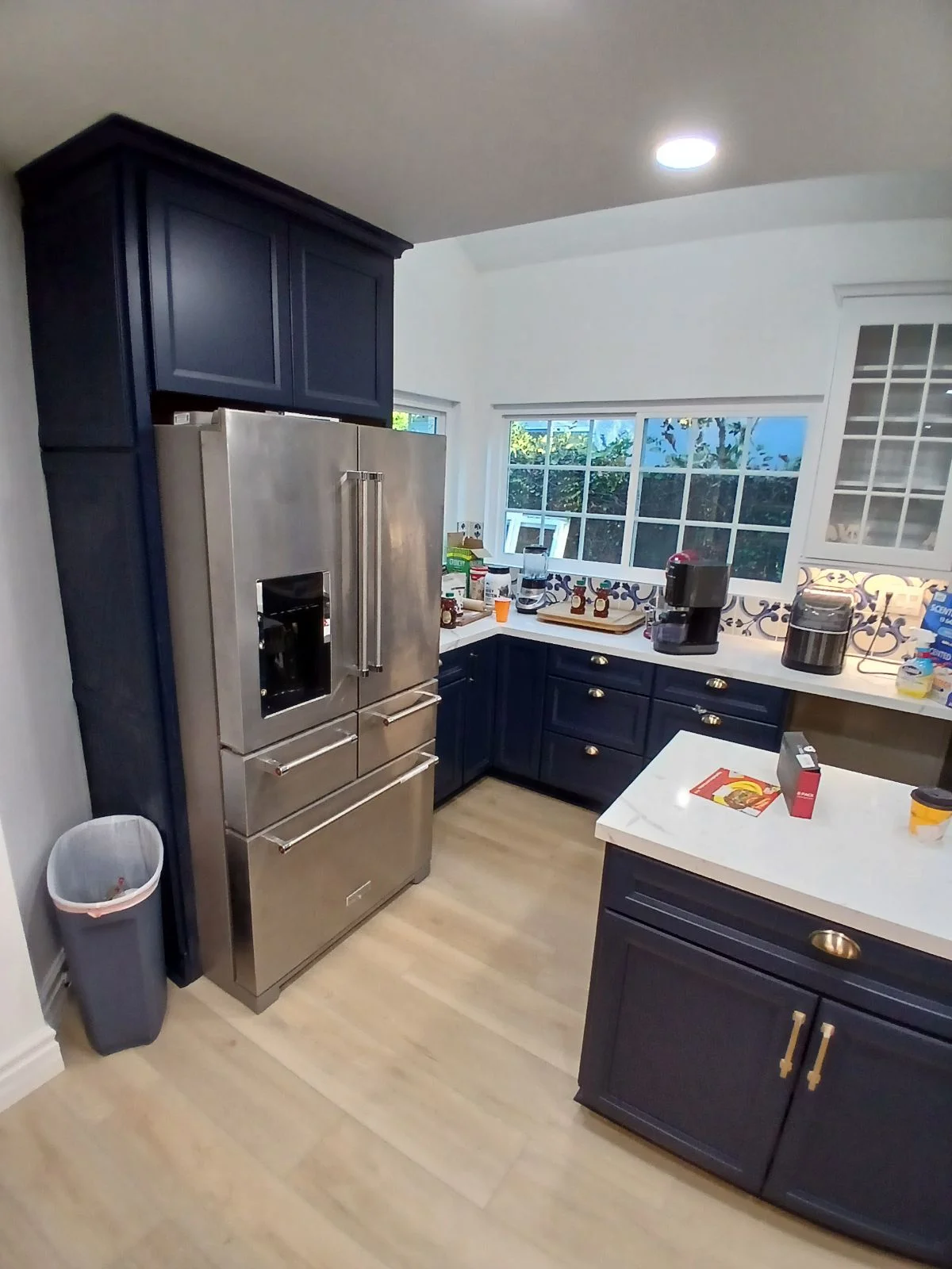 Kitchen with navy cabinetry, stainless steel appliances, white quartz counters, and light wood flooring