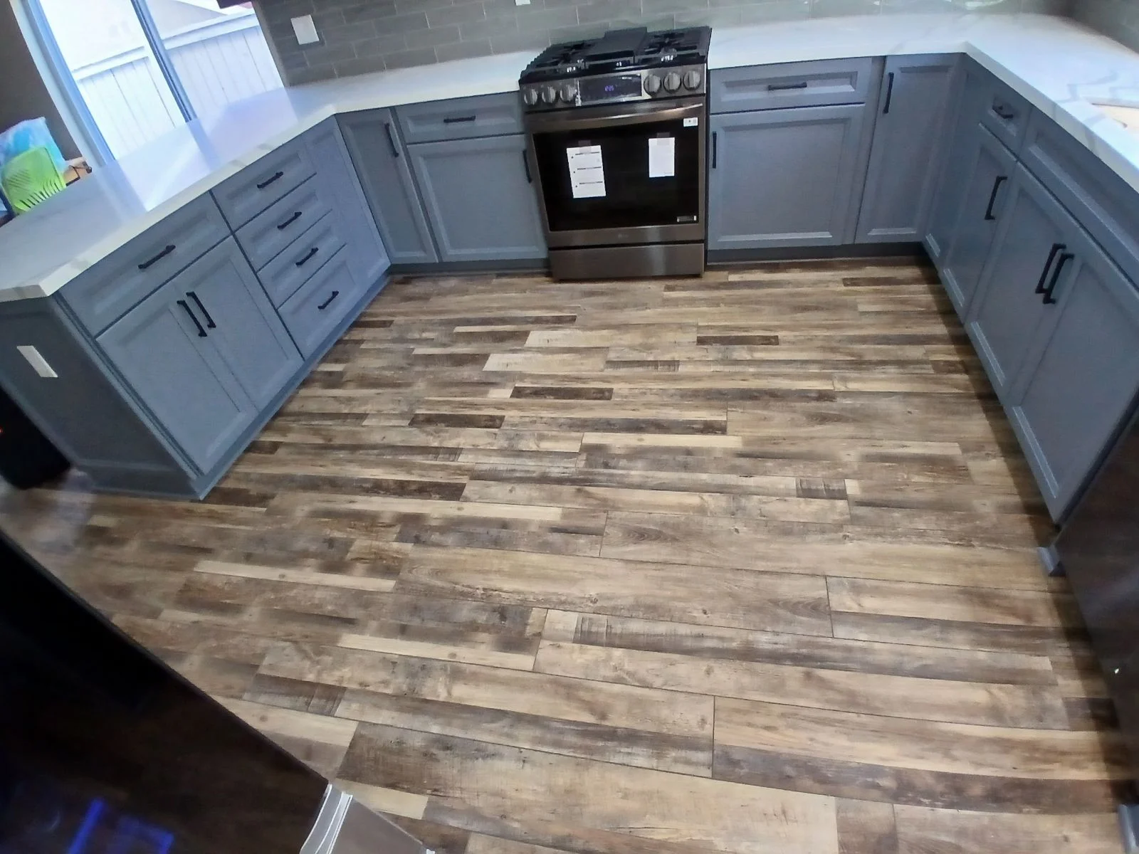 Kitchen with gray cabinetry, stainless steel range, and wood-look plank flooring in mixed tones