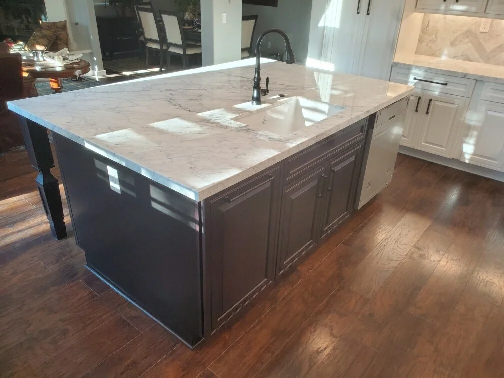 Marble-topped kitchen island with dark cabinetry, undermount sink, and oil-rubbed bronze faucet