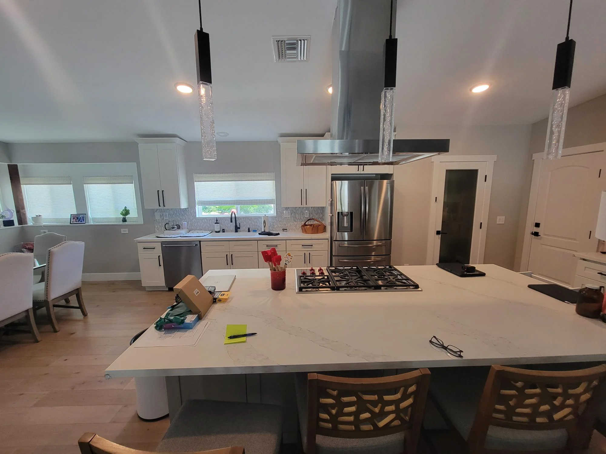 Modern kitchen with white cabinetry, stainless steel appliances, quartz island, and pendant lighting