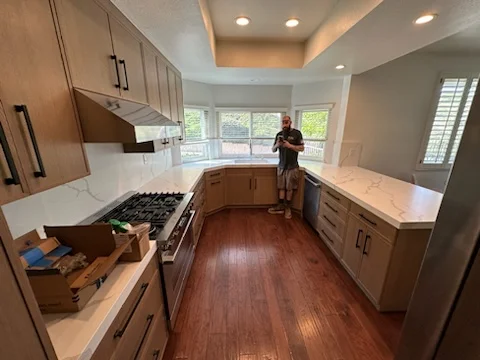 Modern kitchen with wood cabinetry, stainless steel appliances, quartz counters, and hardwood flooring