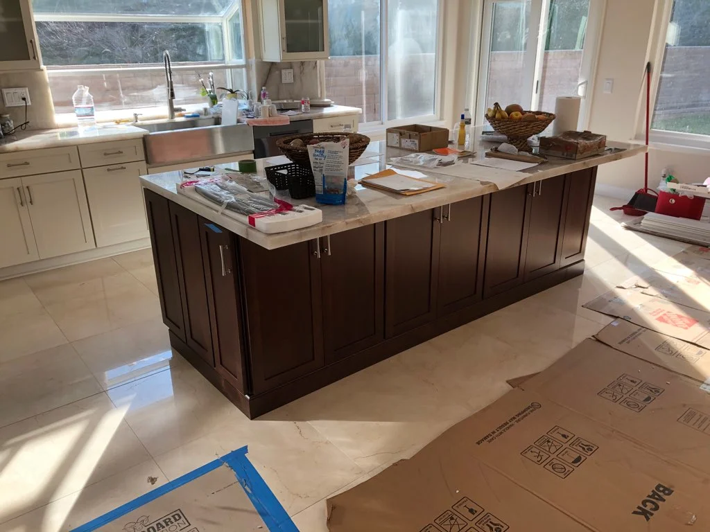 Dark wood kitchen island with quartz countertop and stainless steel sink during installation