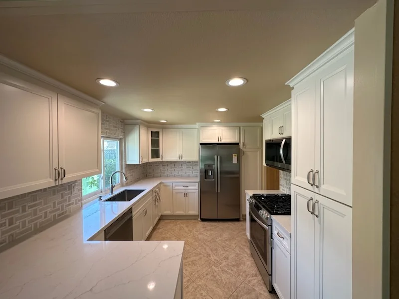 White kitchen with custom cabinetry, subway tile backsplash, quartz counters, and stainless steel appliances