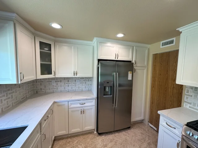 White kitchen cabinets, gray subway tile backsplash, quartz counters, stainless steel appliances