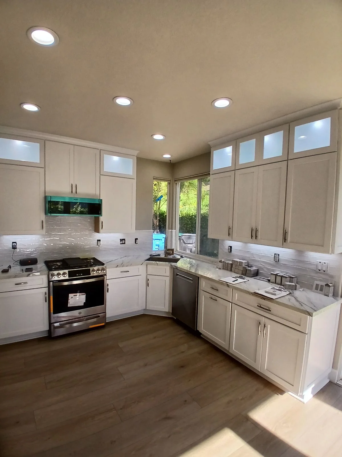 Kitchen with cream cabinetry, marble counters, subway tile backsplash, stainless appliances, and hardwood floors