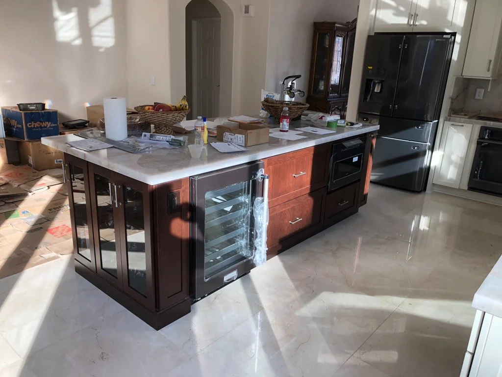 Dark wood kitchen island with quartz countertop, wine cooler, and glass beverage center during installation