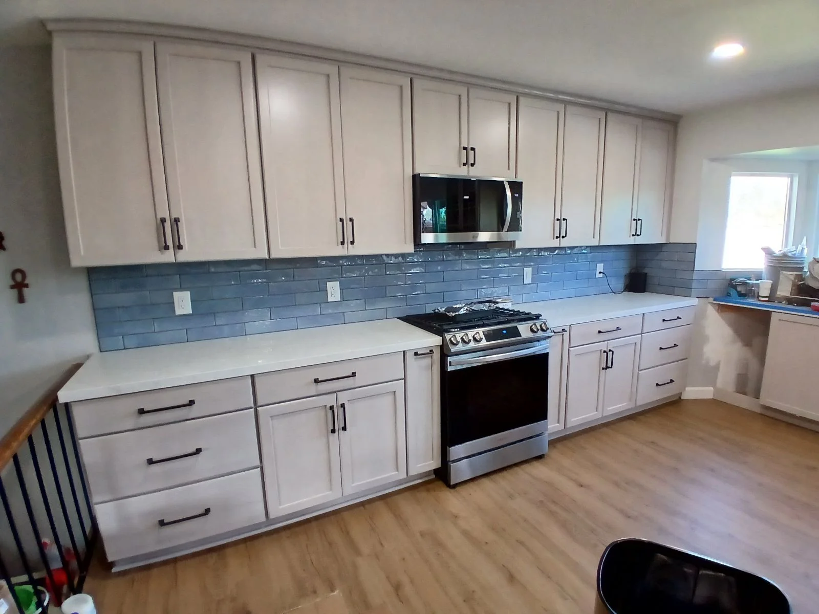 White kitchen cabinets, blue subway tile backsplash, stainless steel range, quartz counters