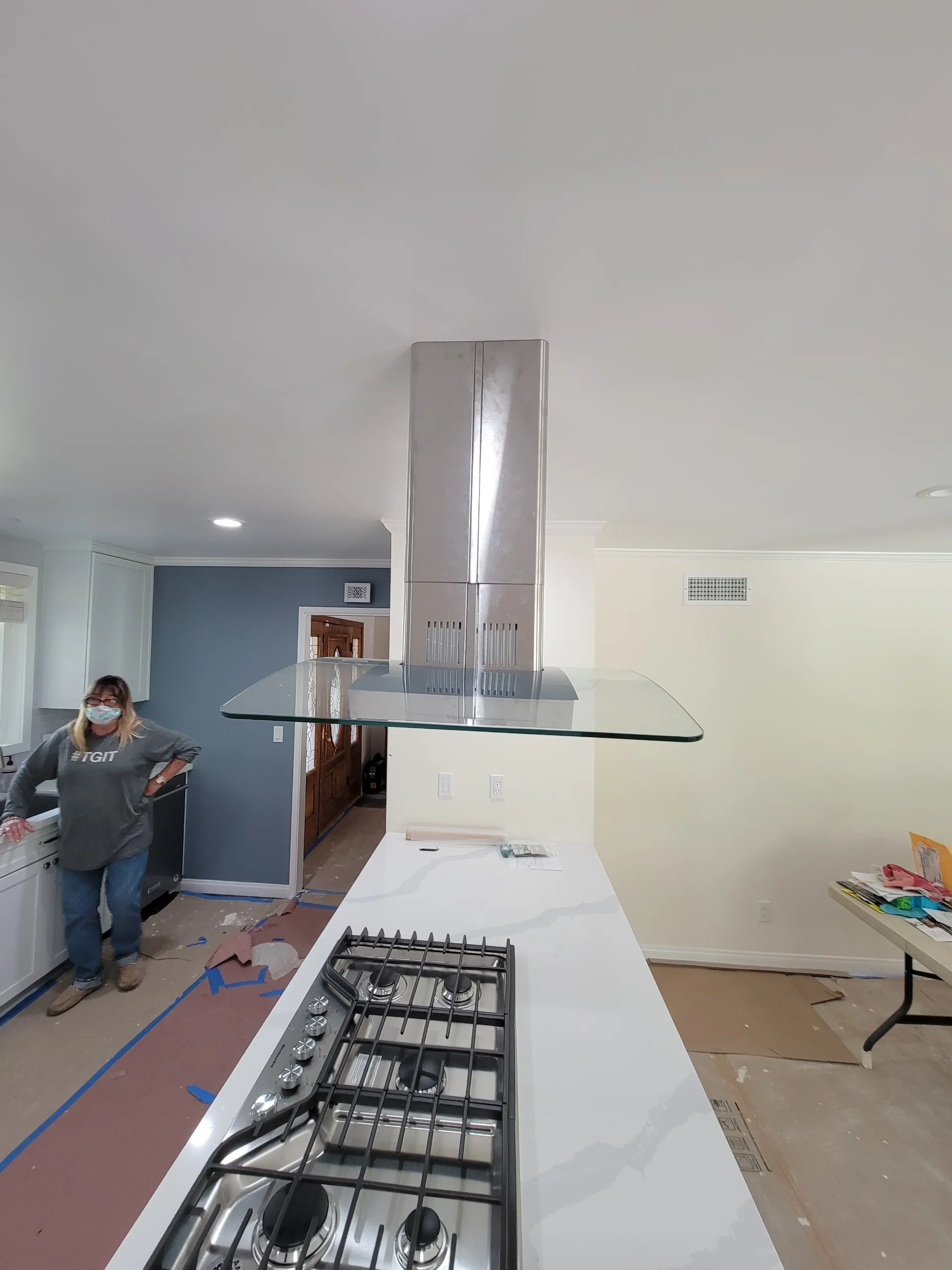 Kitchen island with white countertop, gas range, and stainless steel range hood during installation