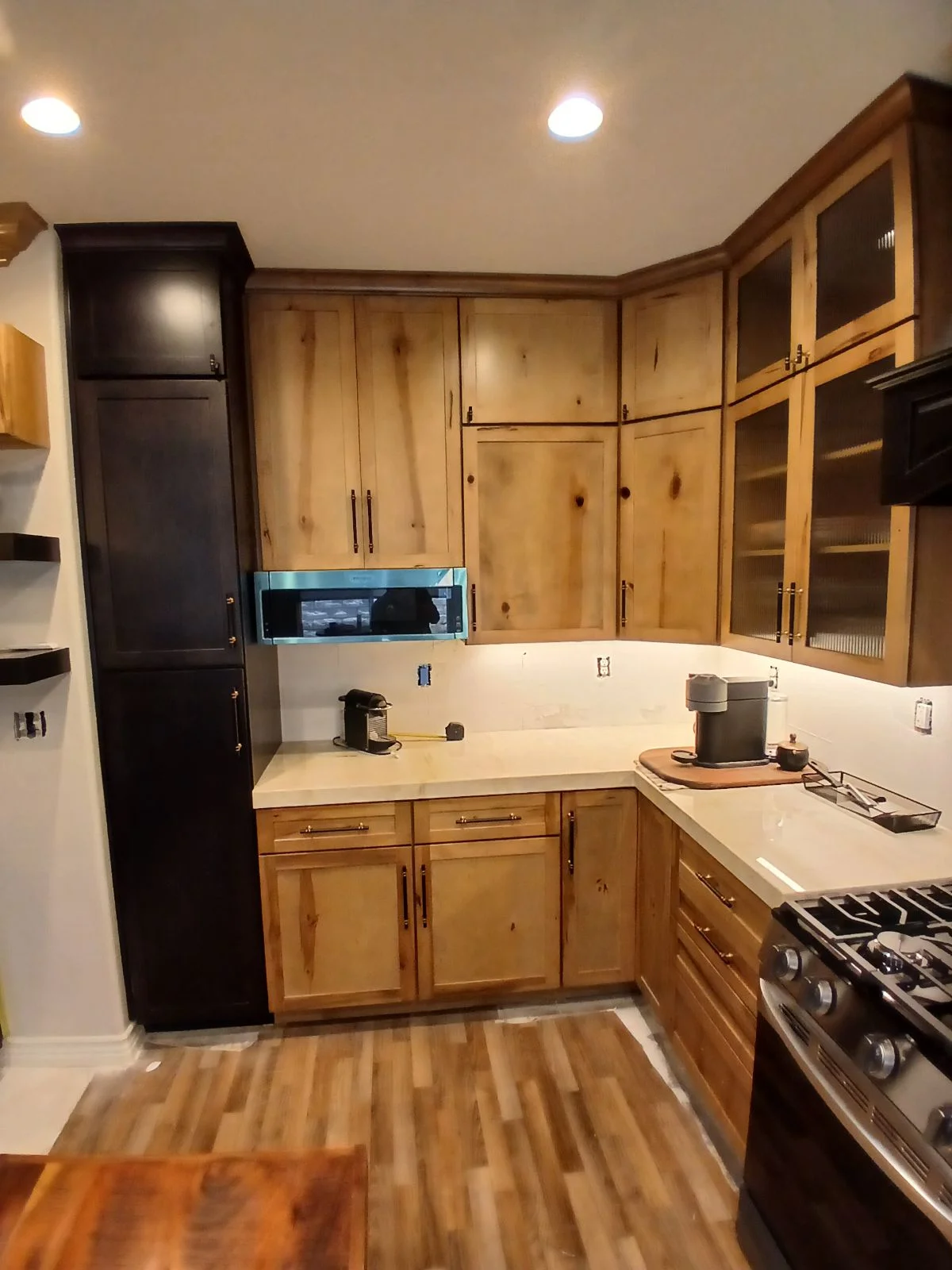 Kitchen with knotty pine cabinets, quartz counters, glass-front uppers, and gas range