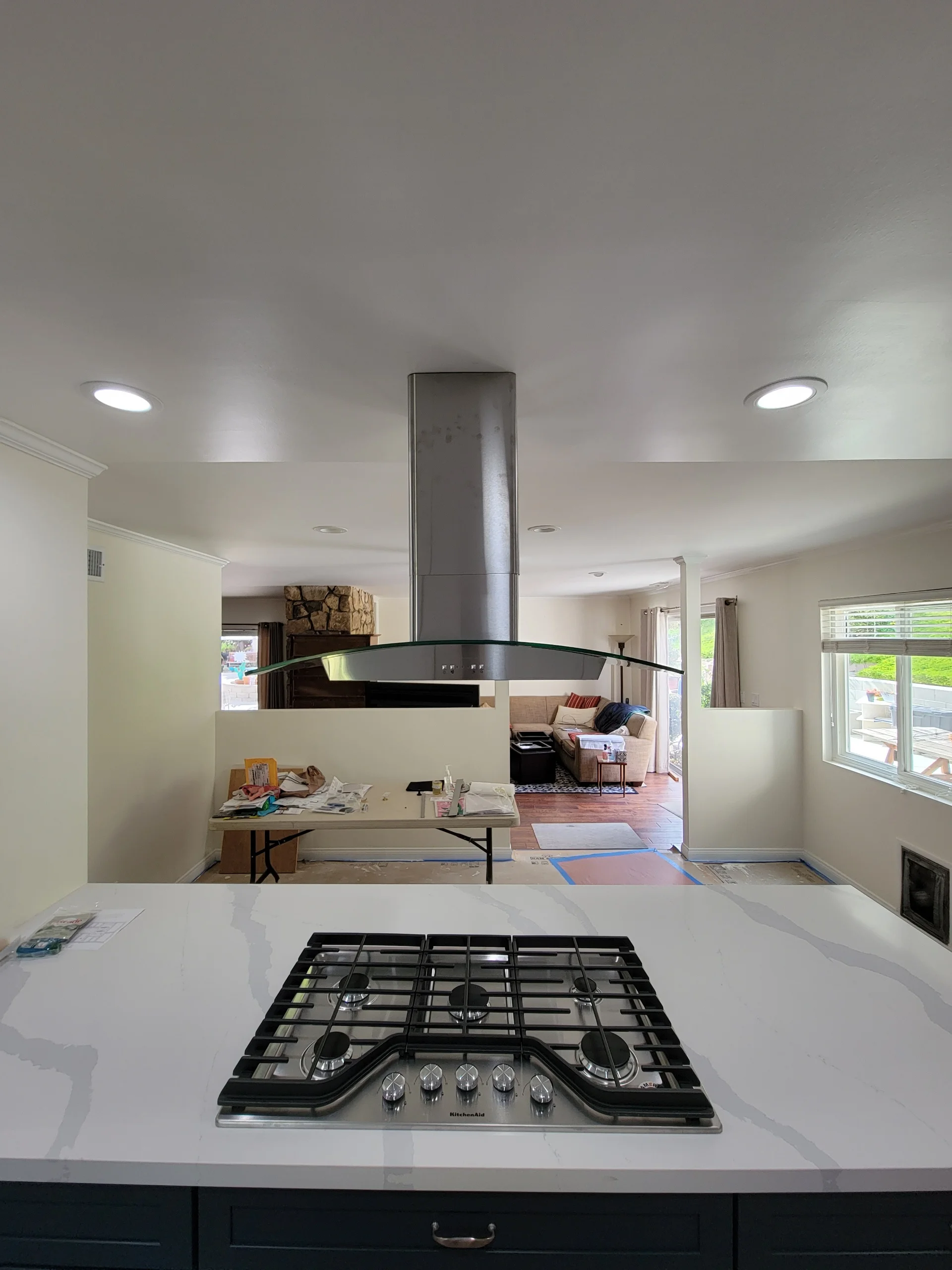 Kitchen island with black gas cooktop, white quartz counters, stainless steel range hood, recessed lighting